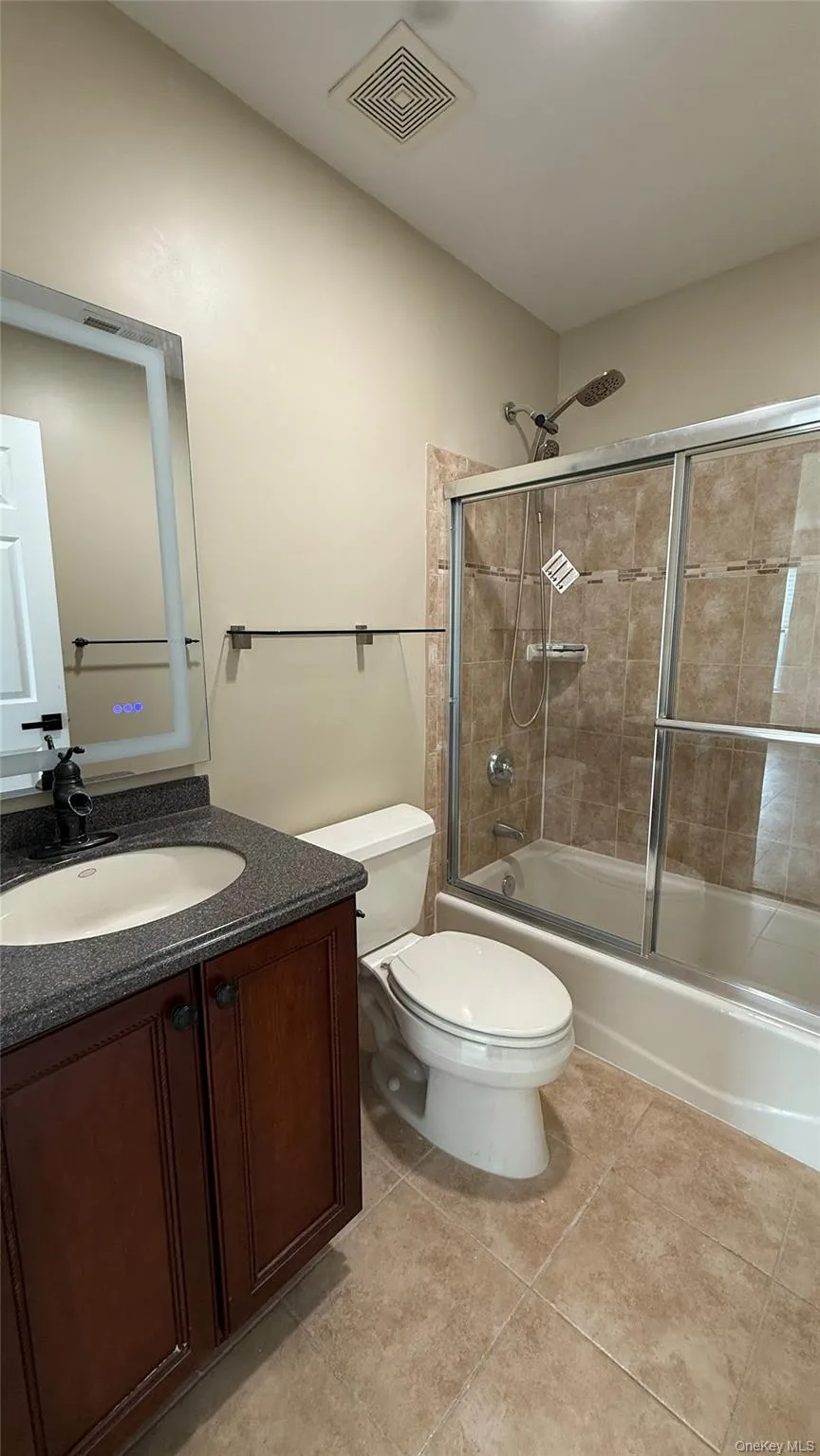 Bathroom featuring vanity, enclosed tub / shower combo, and light tile patterned floors Bathroom featuring vanity, enclosed tub / shower combo, and light tile patterned floors