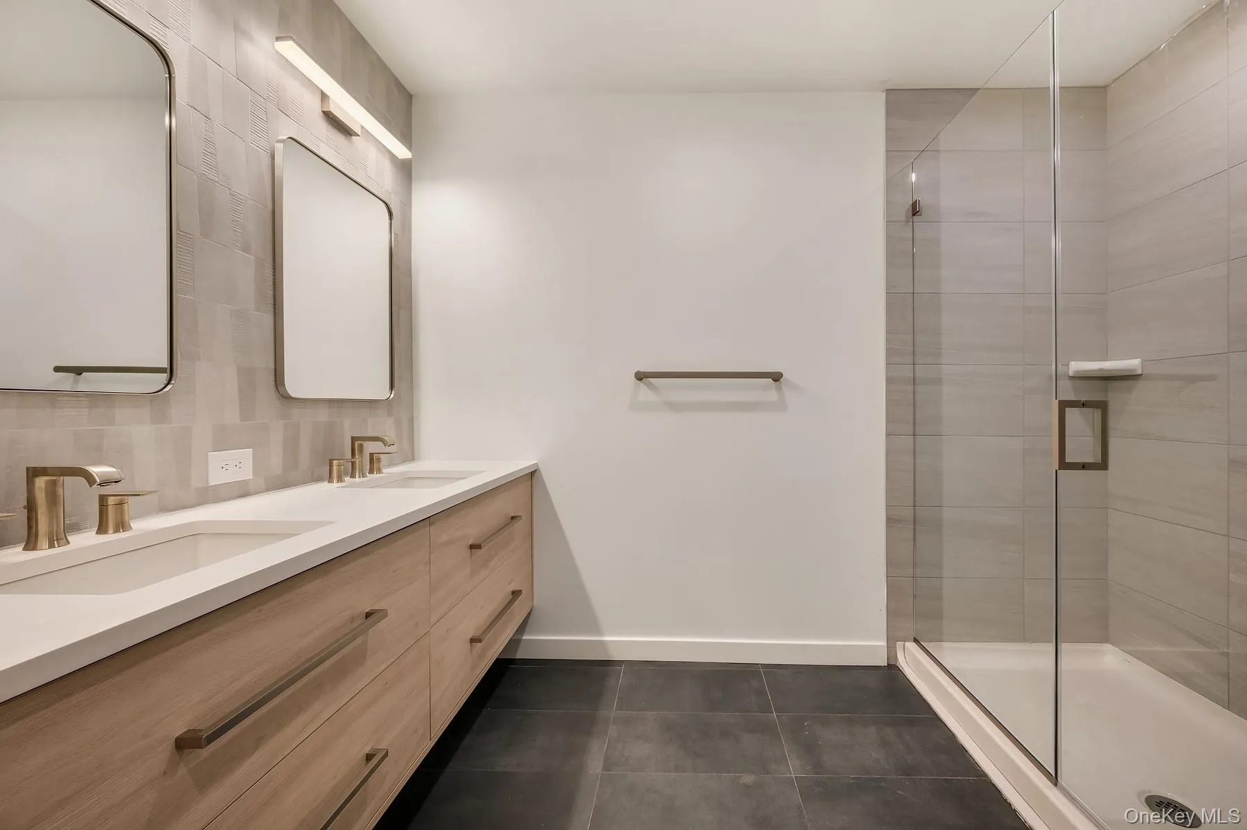 Full bath with double vanity, a shower stall, dark tile patterned floors, and backsplash Full bath with double vanity, a shower stall, dark tile patterned floors, and backsplash