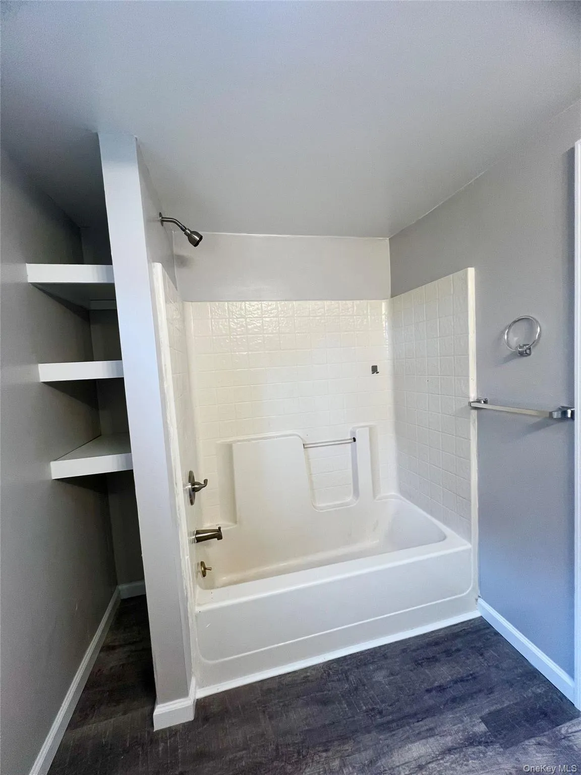 Full bath featuring dark wood-type flooring and shower / tub combination Full bath featuring dark wood-type flooring and shower / tub combination