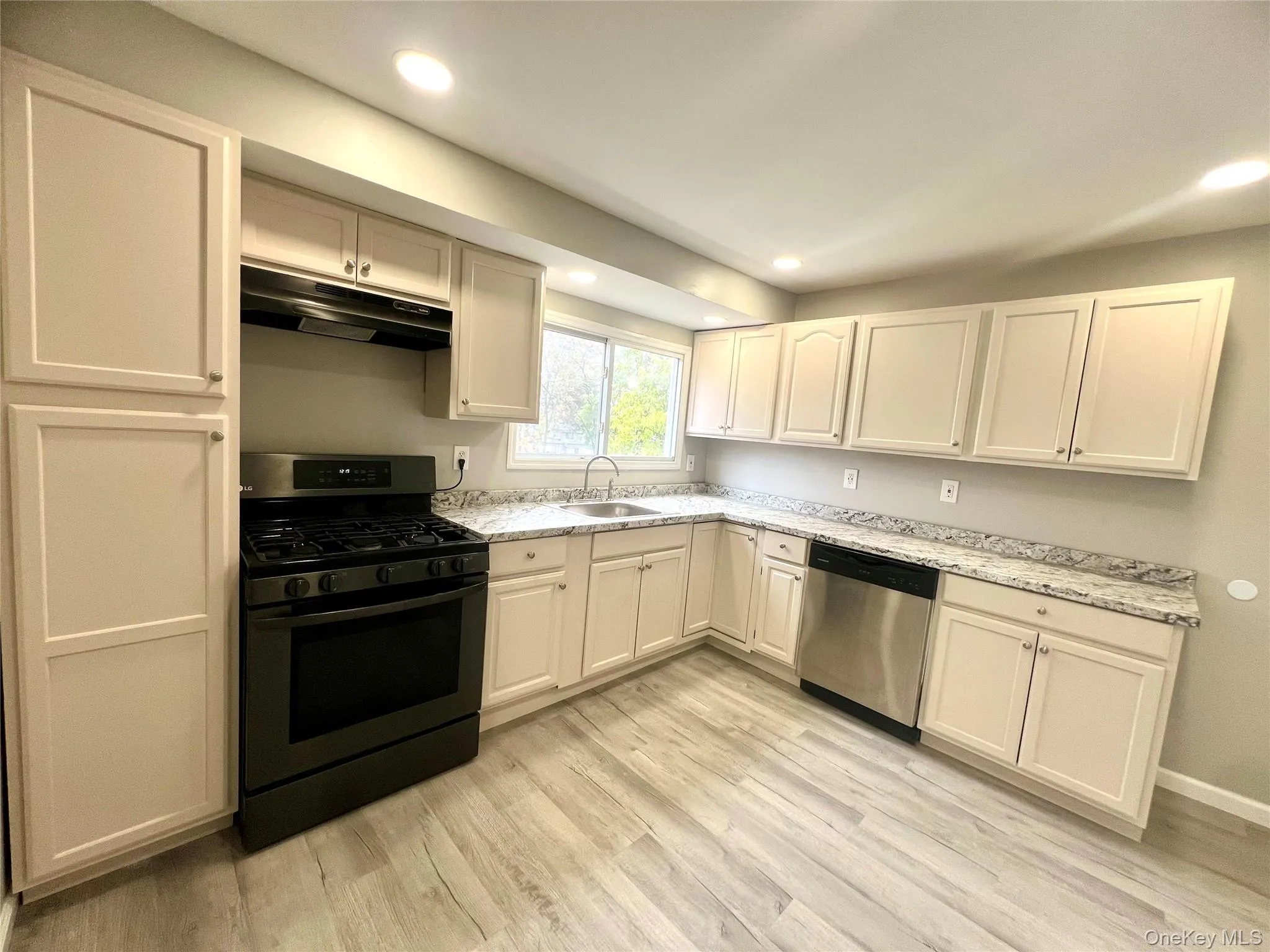 Kitchen with gas range oven, recessed lighting, under cabinet range hood, stainless steel dishwasher, and light wood-type flooring Kitchen with gas range oven, recessed lighting, under cabinet range hood, stainless steel dishwasher, and light wood-type flooring