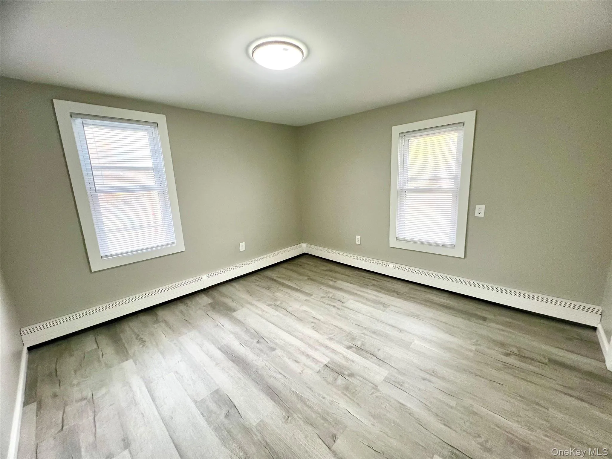 Empty room with baseboard heating and light wood-style flooring Empty room with baseboard heating and light wood-style flooring
