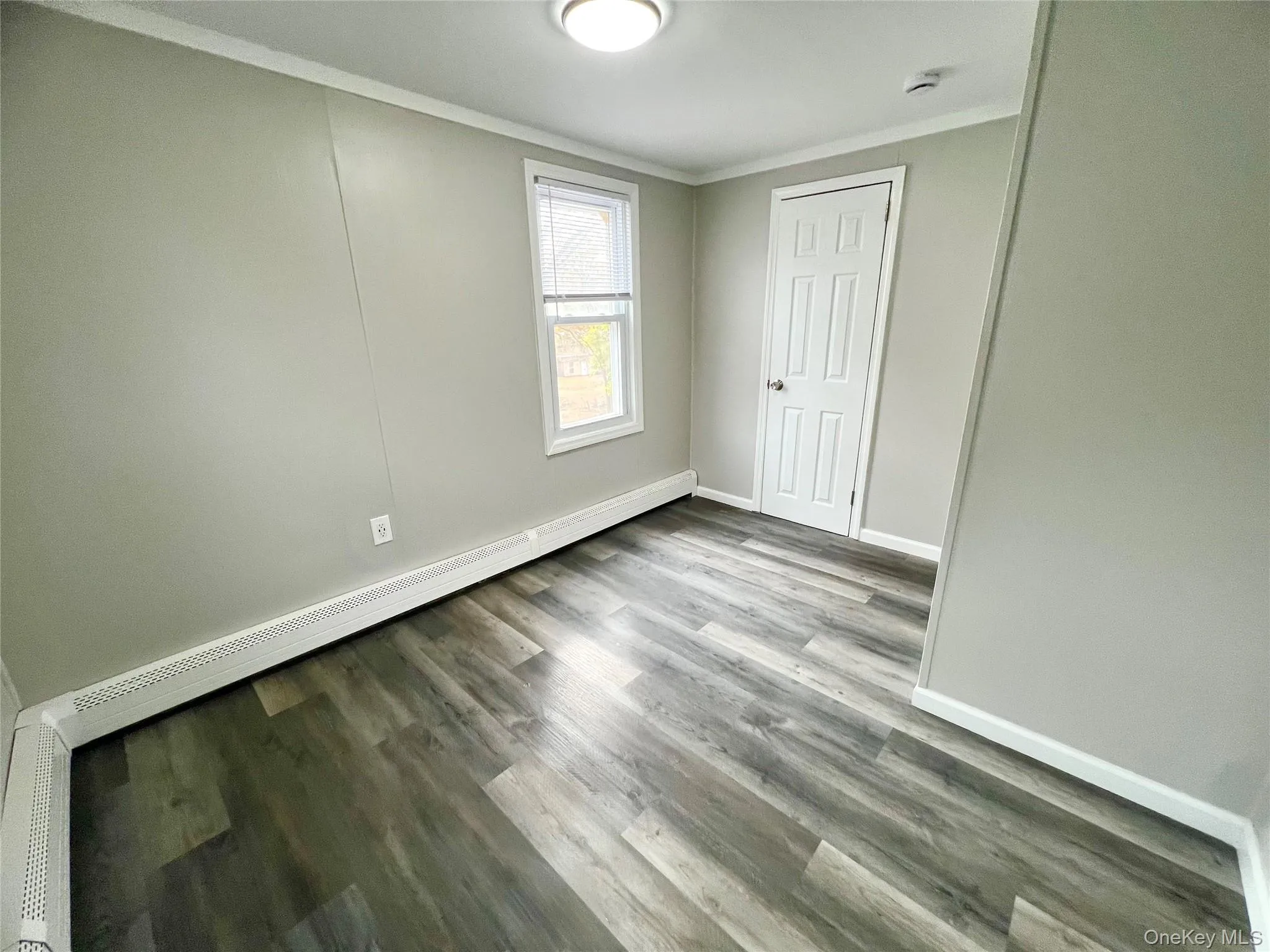 Unfurnished bedroom featuring a baseboard radiator, crown molding, and light wood-style floors Unfurnished bedroom featuring a baseboard radiator, crown molding, and light wood-style floors