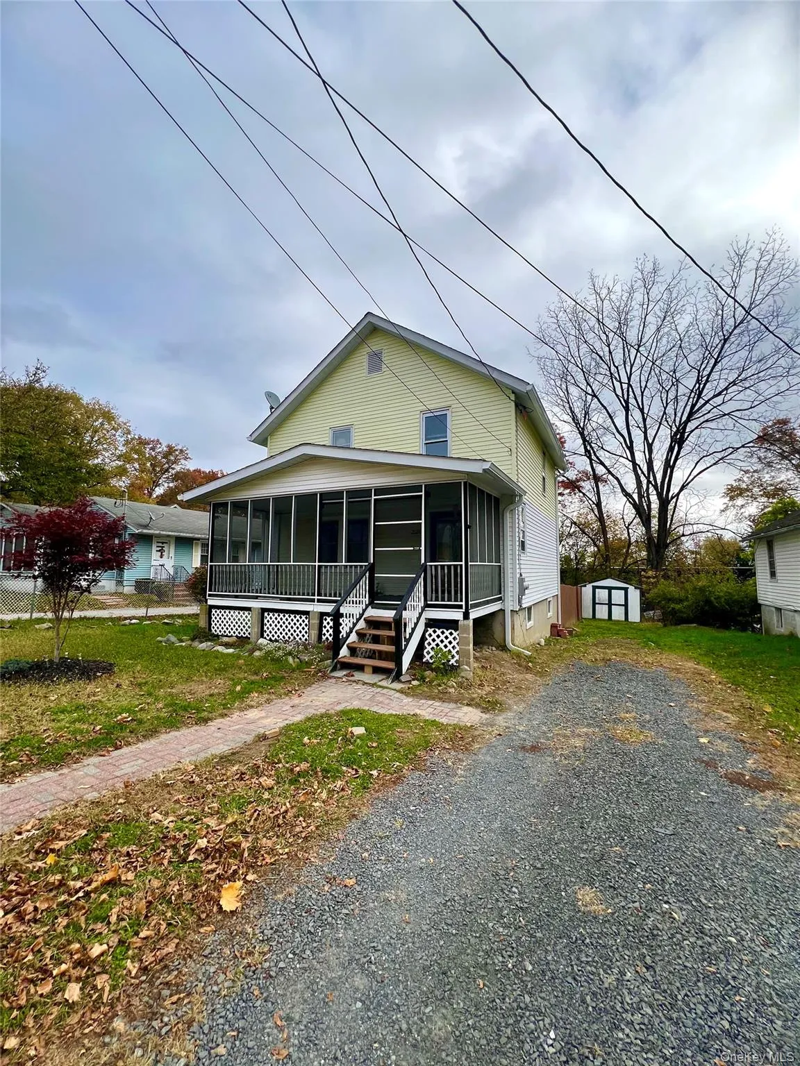 View of front of home featuring a sunroom, a shed, and driveway View of front of home featuring a sunroom, a shed, and driveway
