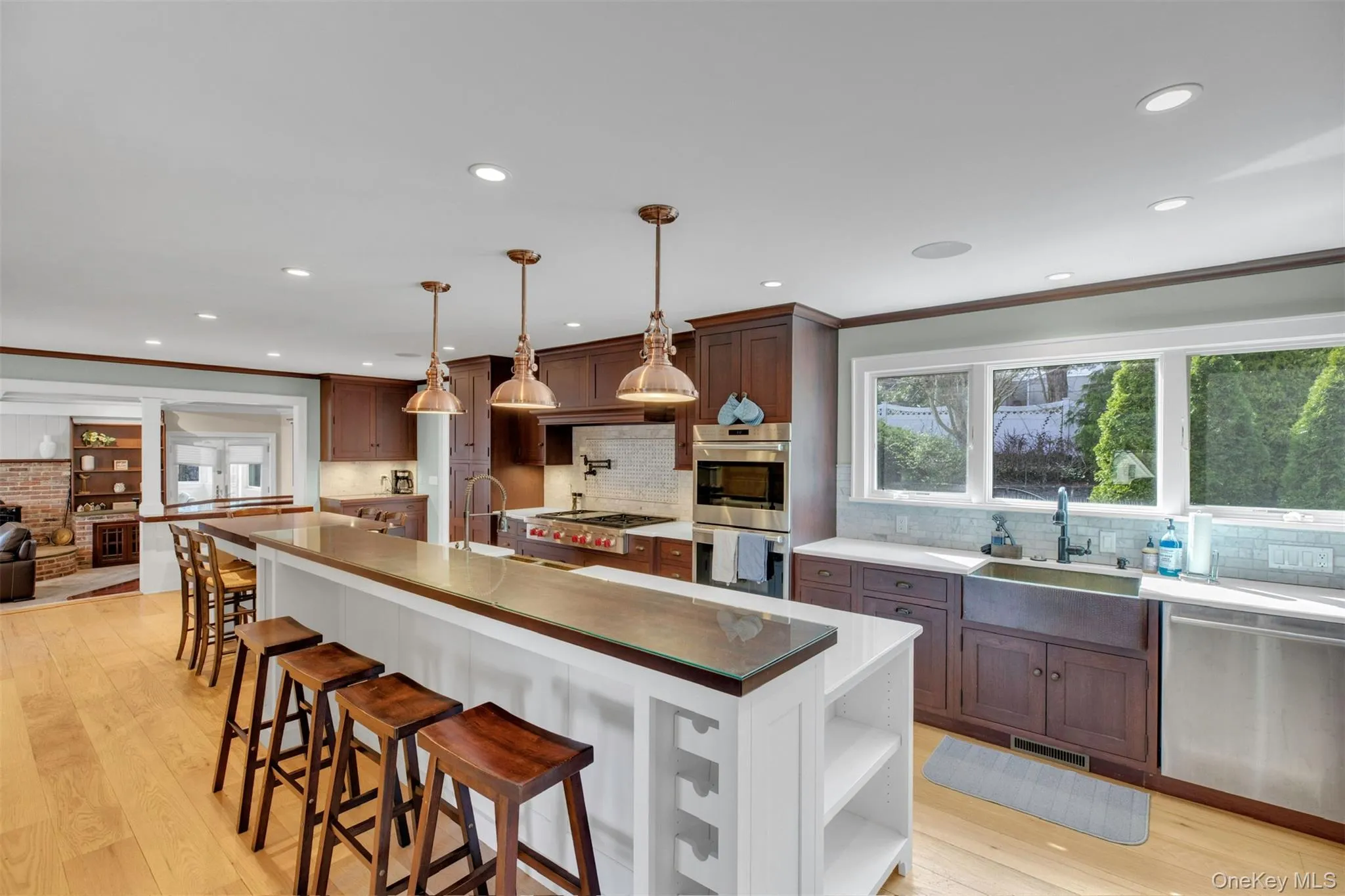 Kitchen with light wood-type flooring, hanging light fixtures, a kitchen breakfast bar, appliances with stainless steel finishes, and ornamental molding Kitchen with light wood-type flooring, hanging light fixtures, a kitchen breakfast bar, appliances with stainless steel finishes, and ornamental molding