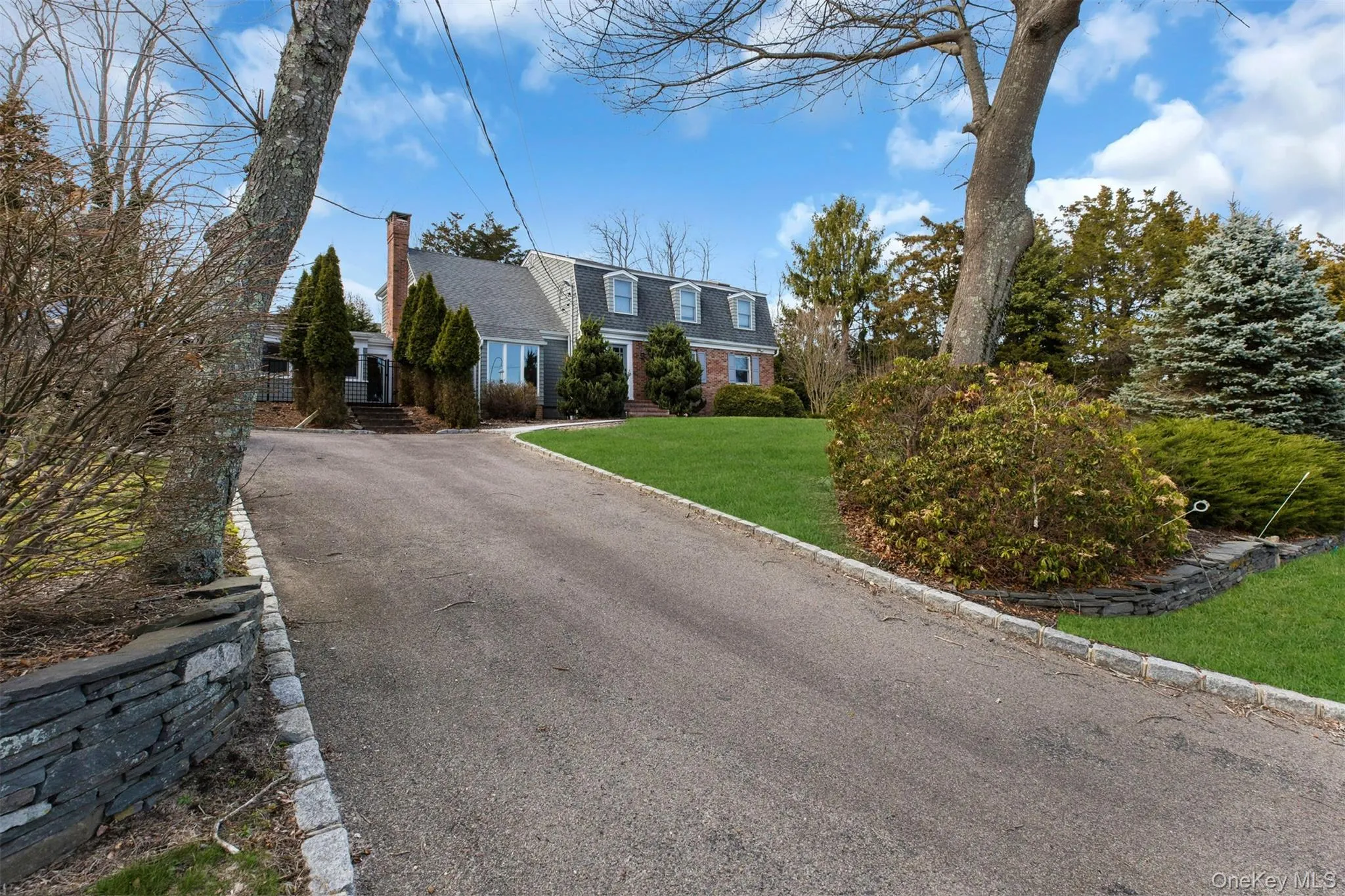 View of front facade featuring a gambrel roof, a front yard, a chimney, asphalt driveway, and roof with shingles View of front facade featuring a gambrel roof, a front yard, a chimney, asphalt driveway, and roof with shingles