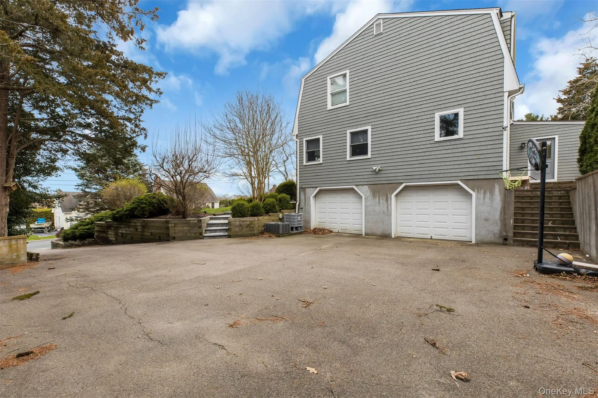 View of property exterior with a gambrel roof, driveway, stairway, and an attached garage View of property exterior with a gambrel roof, driveway, stairway, and an attached garage