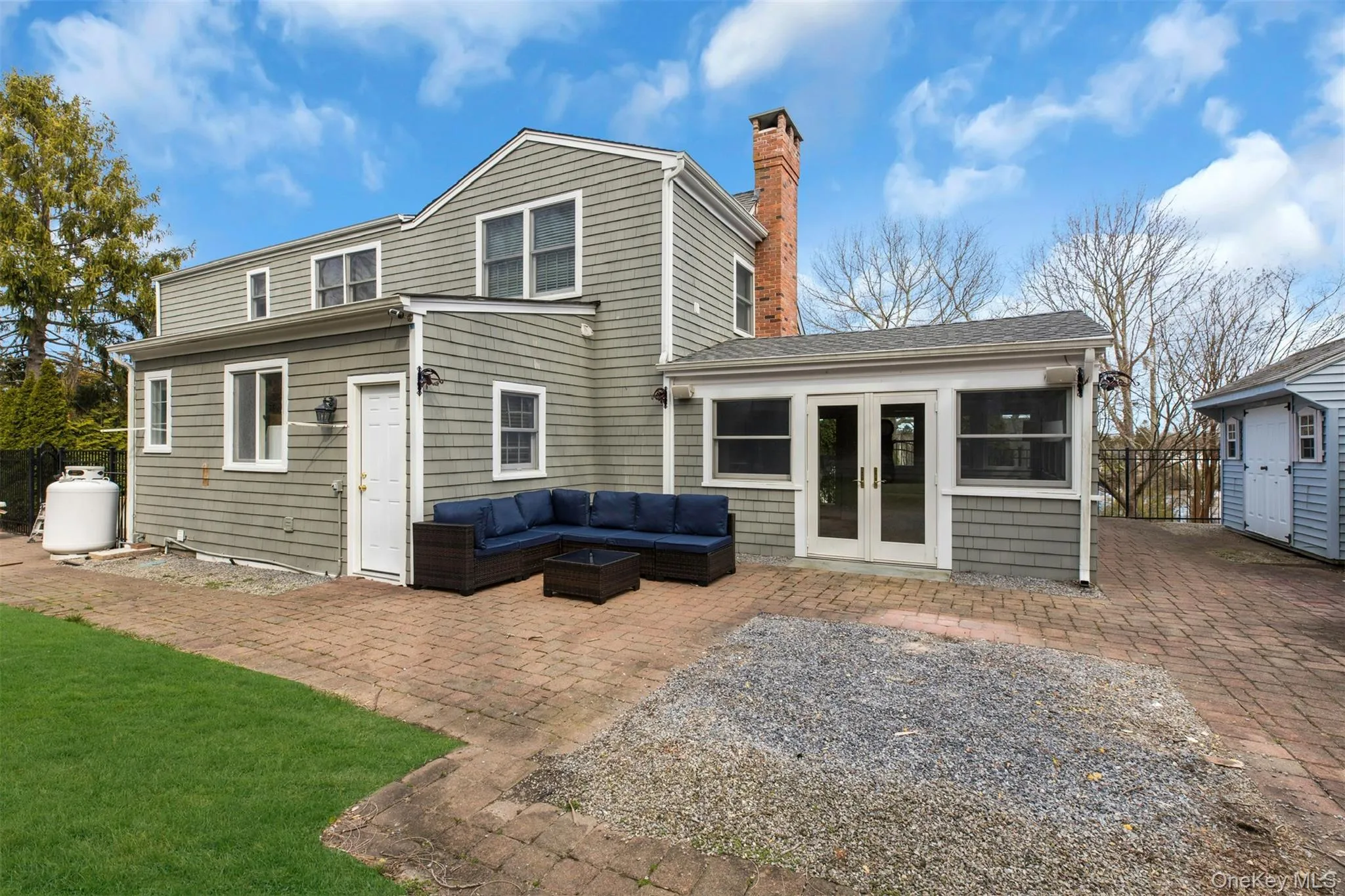 Rear view of house with french doors, outdoor lounge area, a patio area, a chimney, and a sunroom Rear view of house with french doors, outdoor lounge area, a patio area, a chimney, and a sunroom