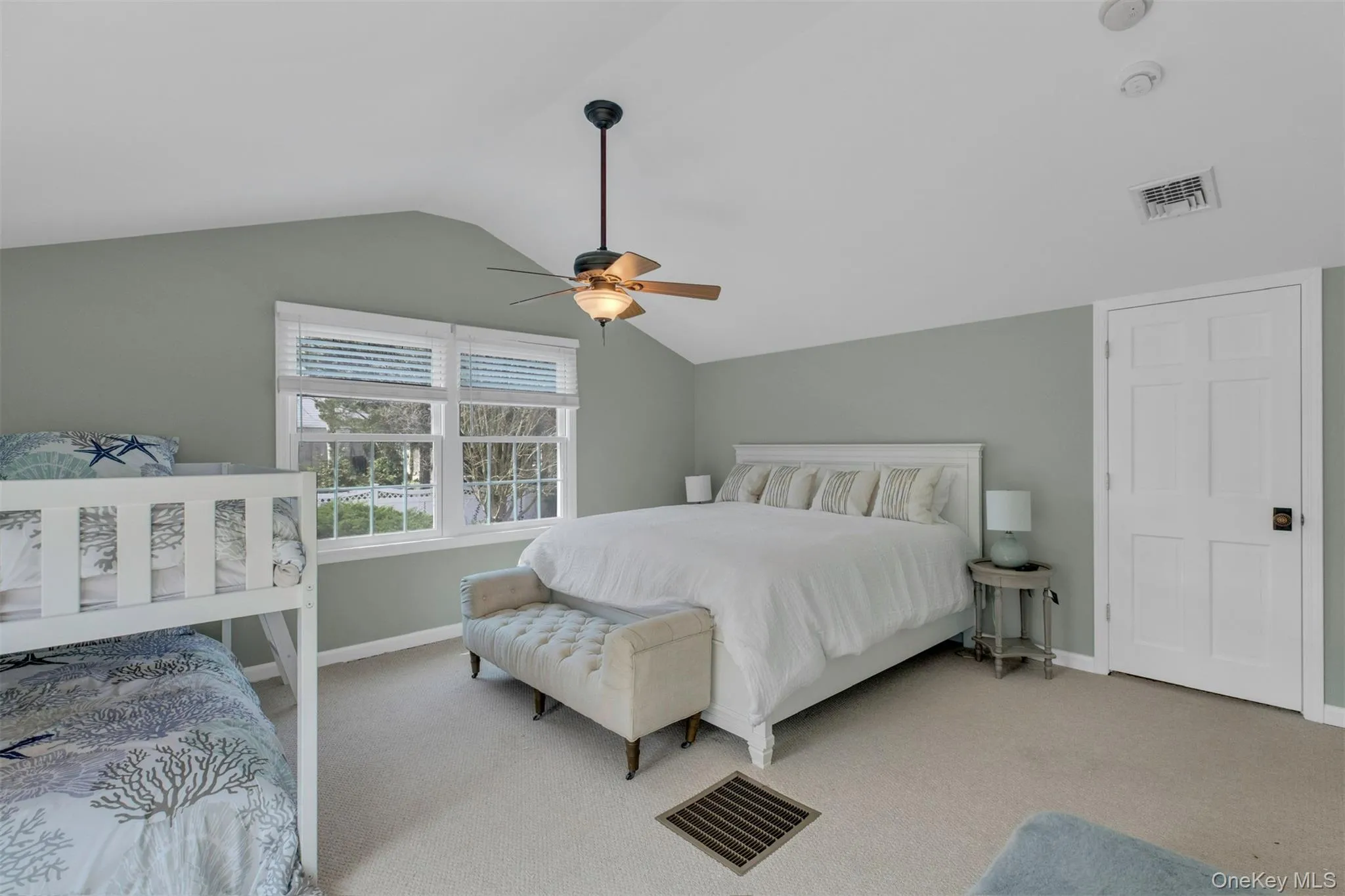 Bedroom featuring light carpet, vaulted ceiling, and a ceiling fan Bedroom featuring light carpet, vaulted ceiling, and a ceiling fan