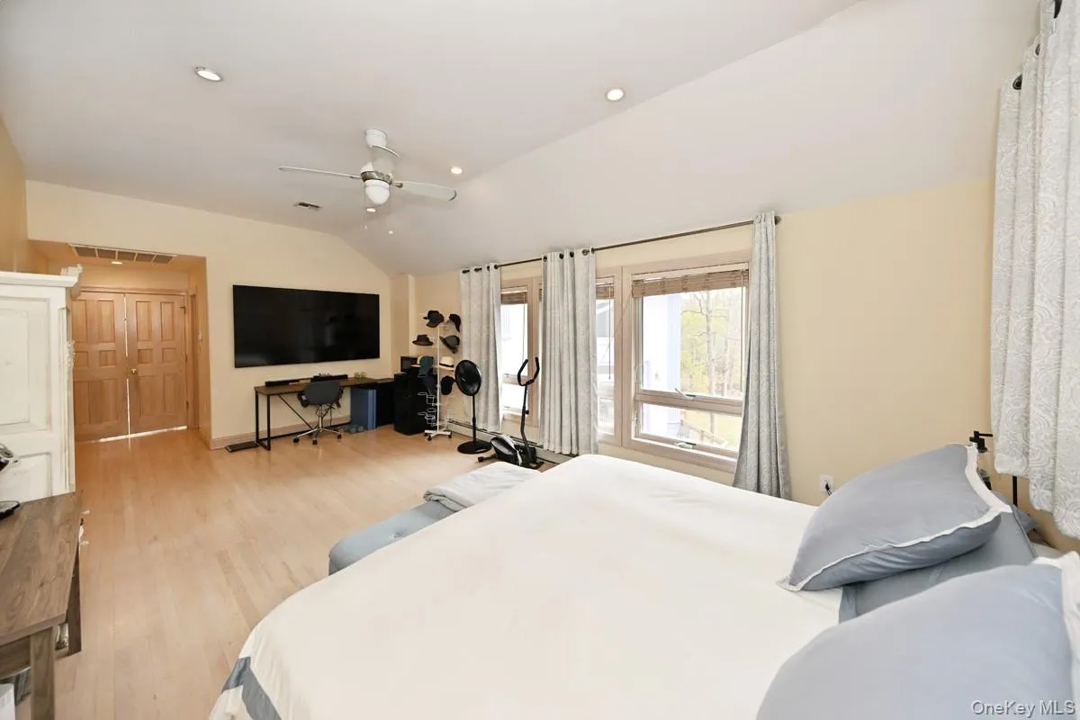 Bedroom featuring lofted ceiling, light wood-style floors, recessed lighting, and a ceiling fan Bedroom featuring lofted ceiling, light wood-style floors, recessed lighting, and a ceiling fan