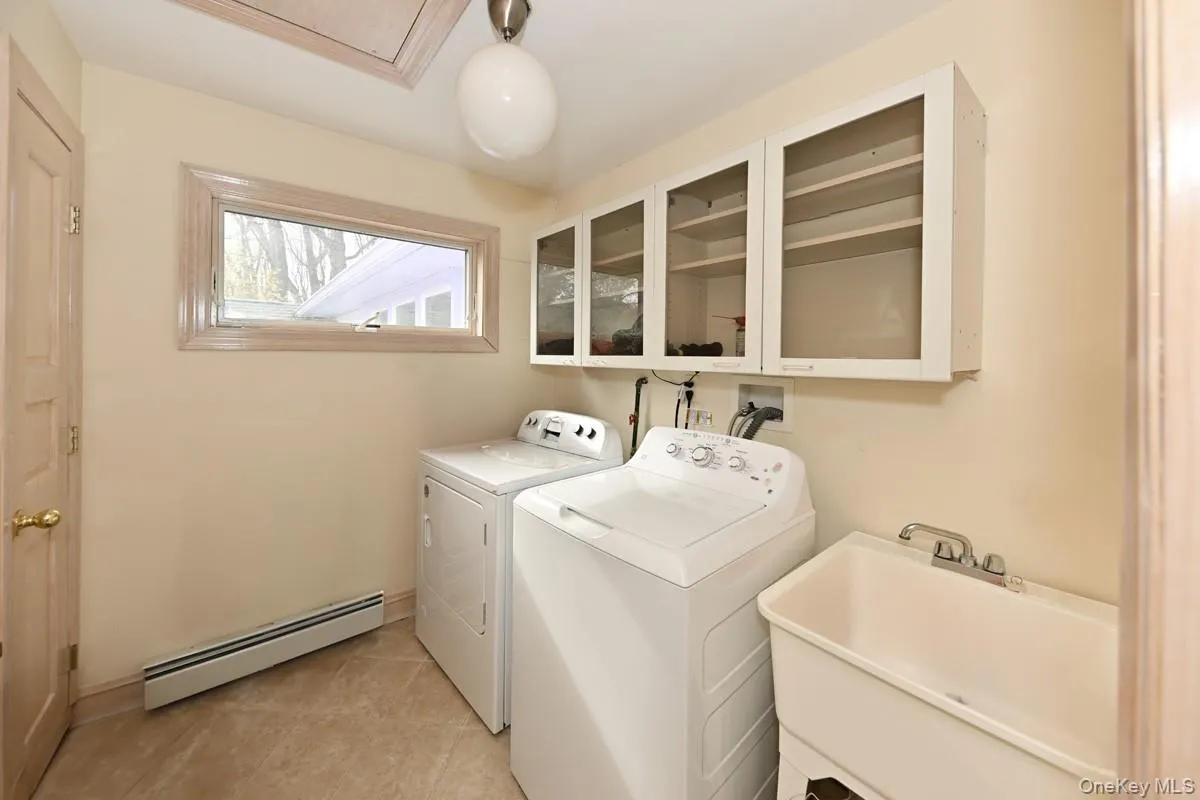 Laundry area with baseboard heating, washing machine and clothes dryer, and light tile patterned floors Laundry area with baseboard heating, washing machine and clothes dryer, and light tile patterned floors
