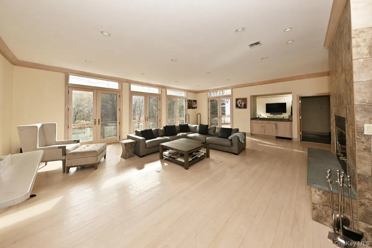 Living room with ornamental molding, french doors, a tiled fireplace, light wood-type flooring, and recessed lighting Living room with ornamental molding, french doors, a tiled fireplace, light wood-type flooring, and recessed lighting