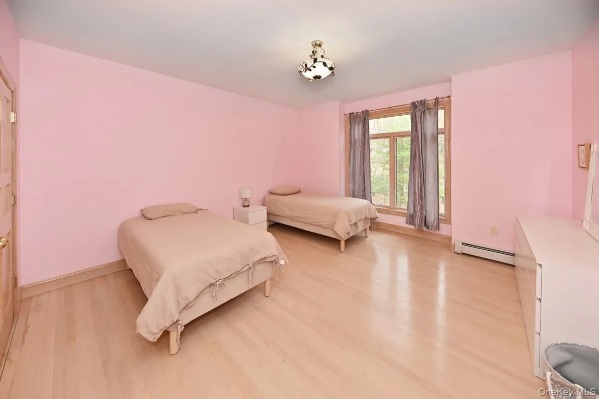 Bedroom with light wood-style flooring and a baseboard radiator Bedroom with light wood-style flooring and a baseboard radiator
