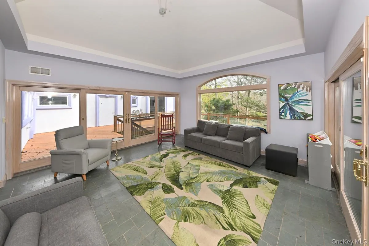 Living room featuring a tray ceiling and stone tile floors Living room featuring a tray ceiling and stone tile floors