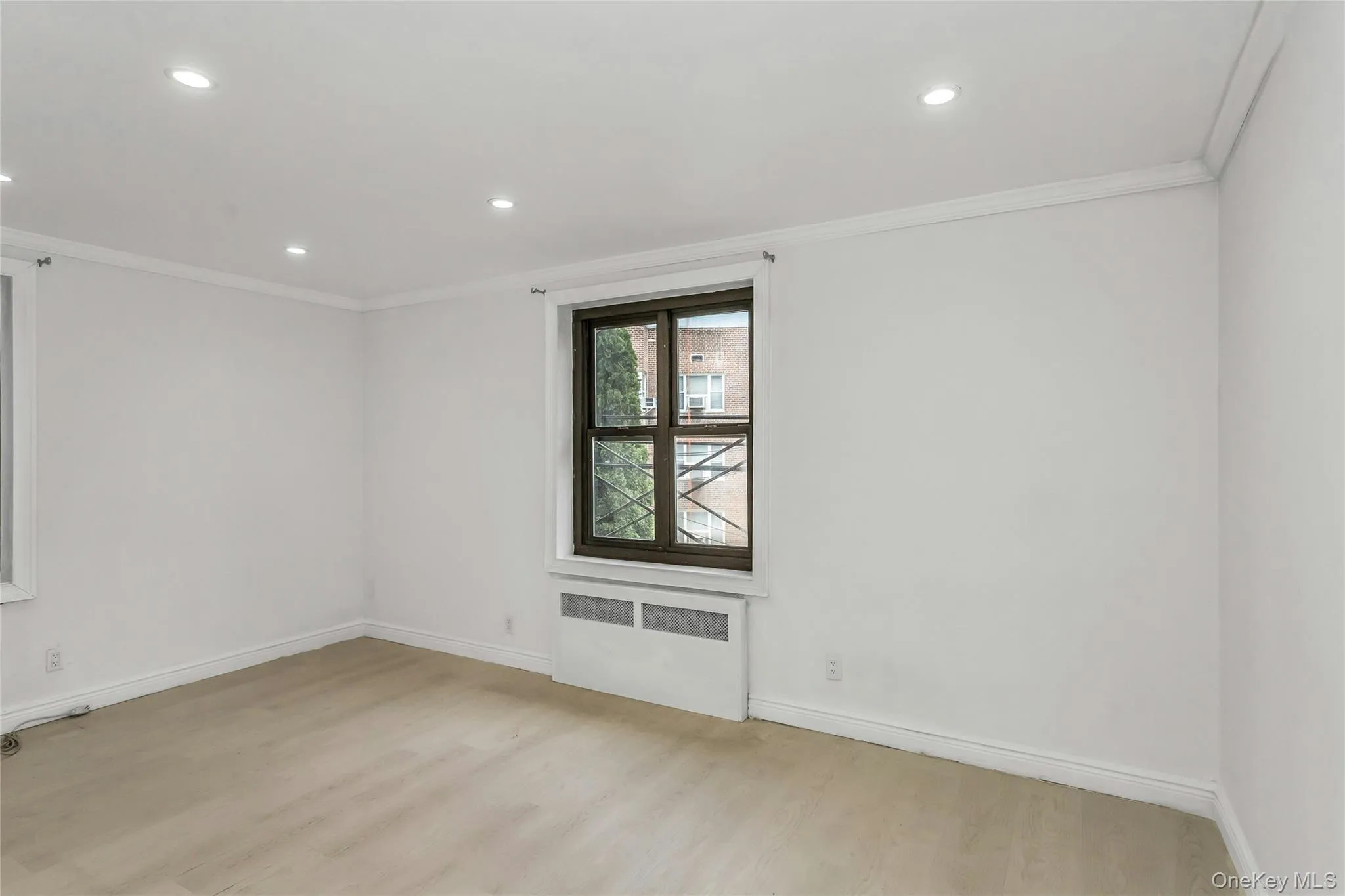 Unfurnished room featuring radiator heating unit, crown molding, light wood finished floors, and recessed lighting Unfurnished room featuring radiator heating unit, crown molding, light wood finished floors, and recessed lighting