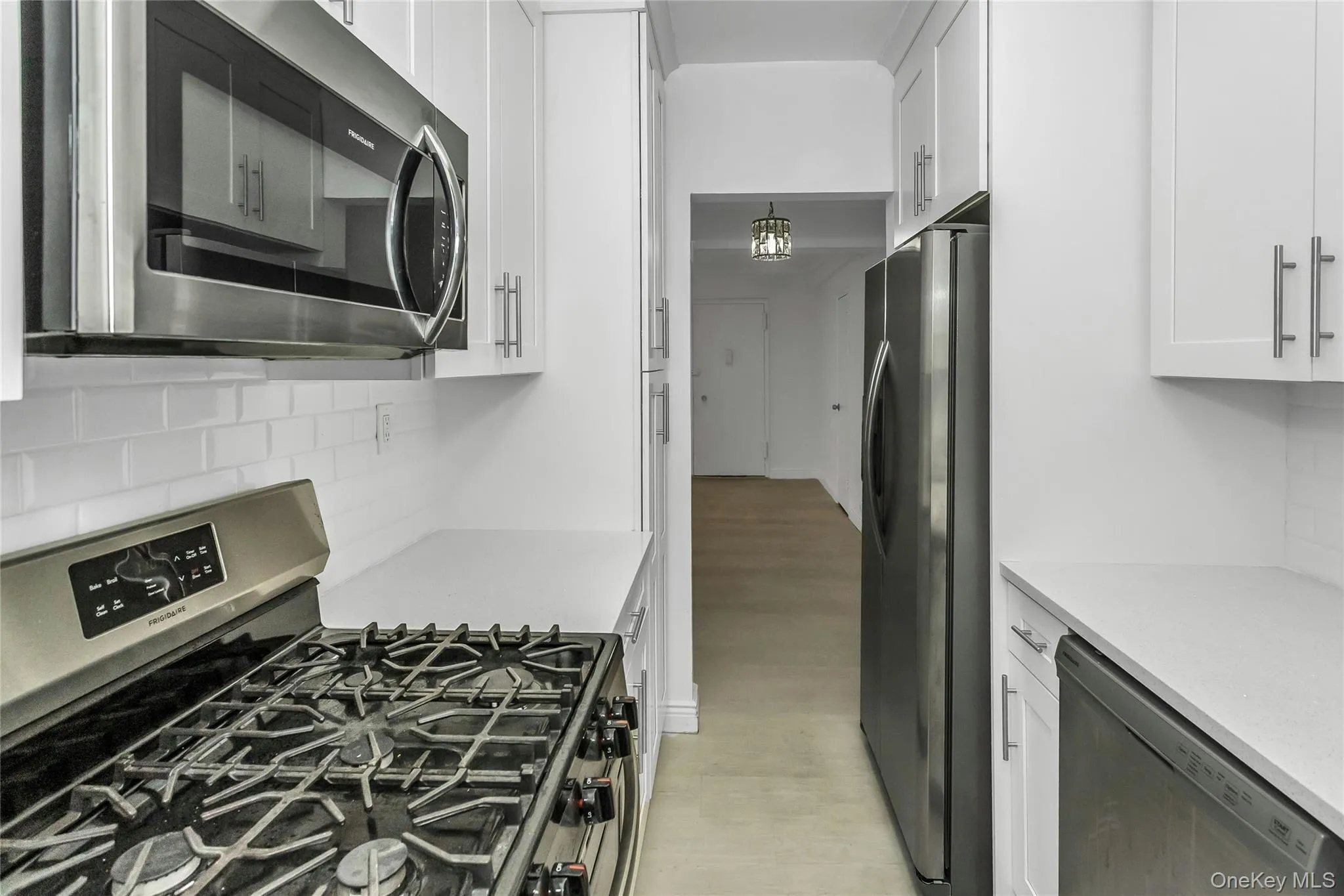 Kitchen featuring tasteful backsplash, appliances with stainless steel finishes, and white cabinets Kitchen featuring tasteful backsplash, appliances with stainless steel finishes, and white cabinets