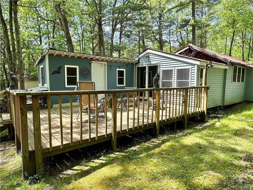 Rear view of property featuring a wooden deck and view of scattered trees Rear view of property featuring a wooden deck and view of scattered trees
