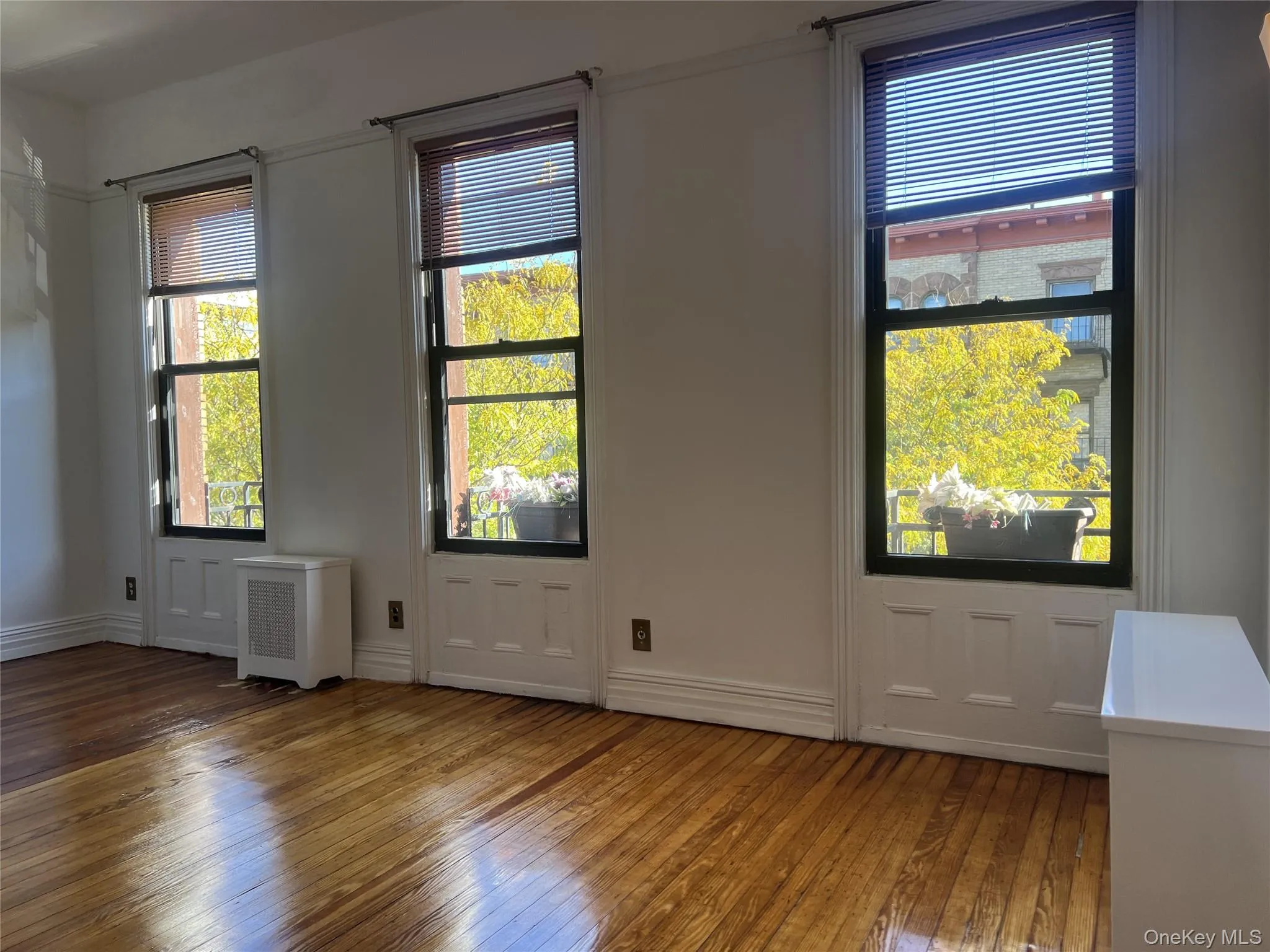Spare room with plenty of natural light, radiator, and hardwood / wood-style flooring Spare room with plenty of natural light, radiator, and hardwood / wood-style flooring