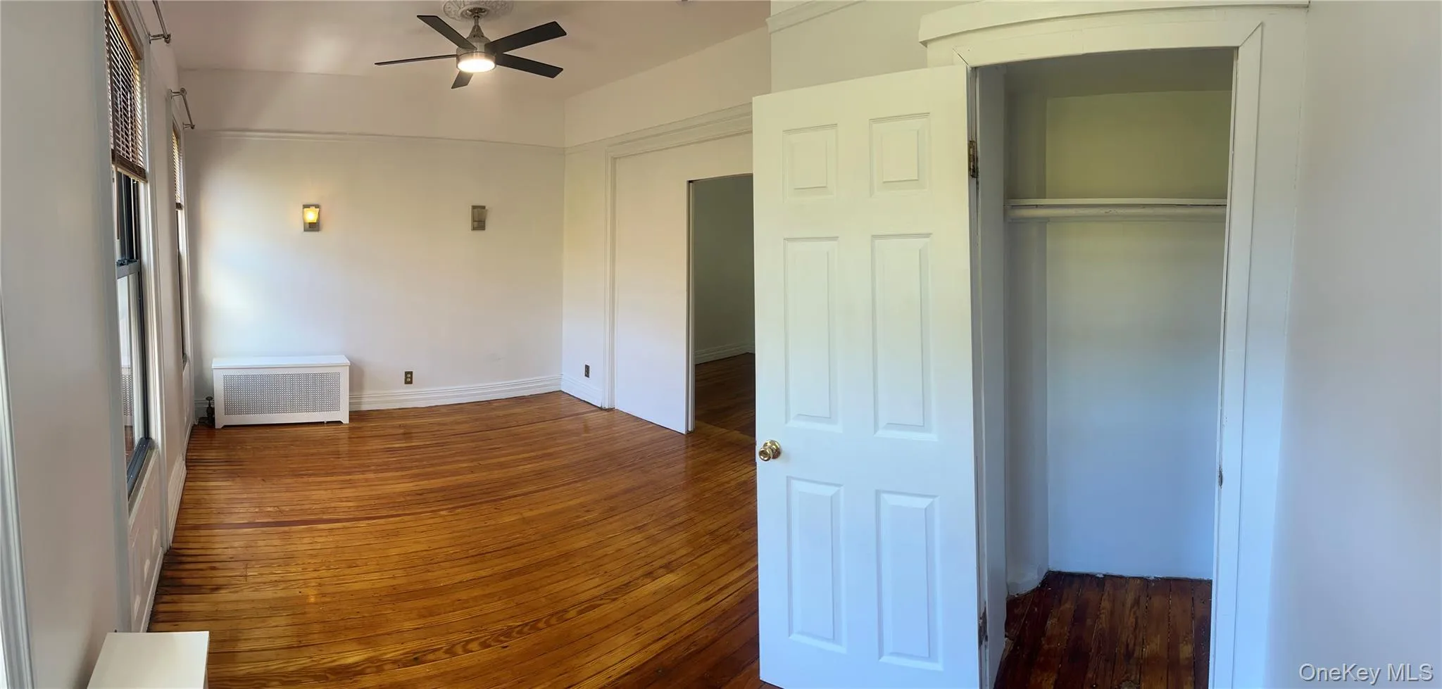 Unfurnished bedroom with radiator, dark wood-style floors, and a ceiling fan Unfurnished bedroom with radiator, dark wood-style floors, and a ceiling fan