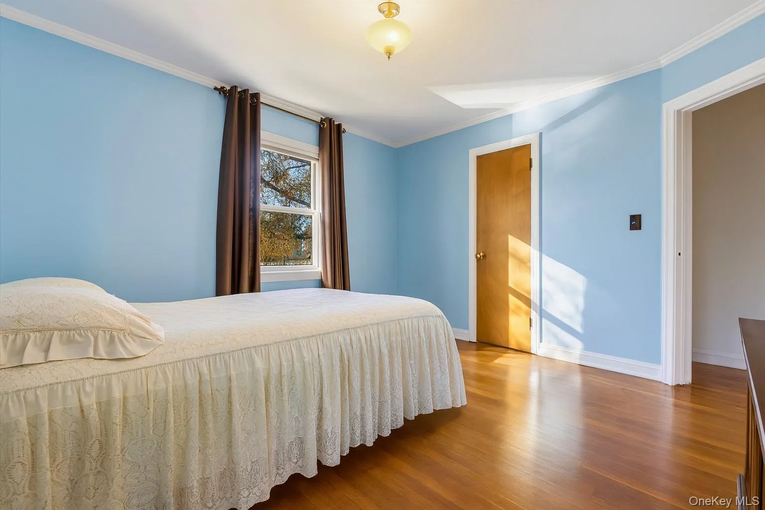 Bedroom with ornamental molding and wood finished floors Bedroom with ornamental molding and wood finished floors