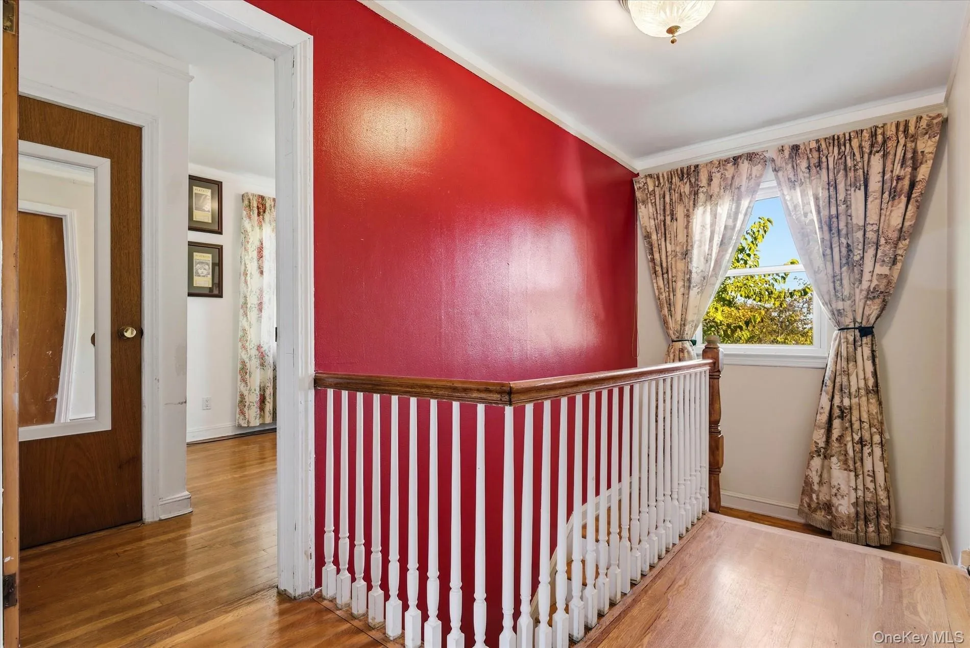 Hallway with wood finished floors, ornamental molding, and an upstairs landing Hallway with wood finished floors, ornamental molding, and an upstairs landing