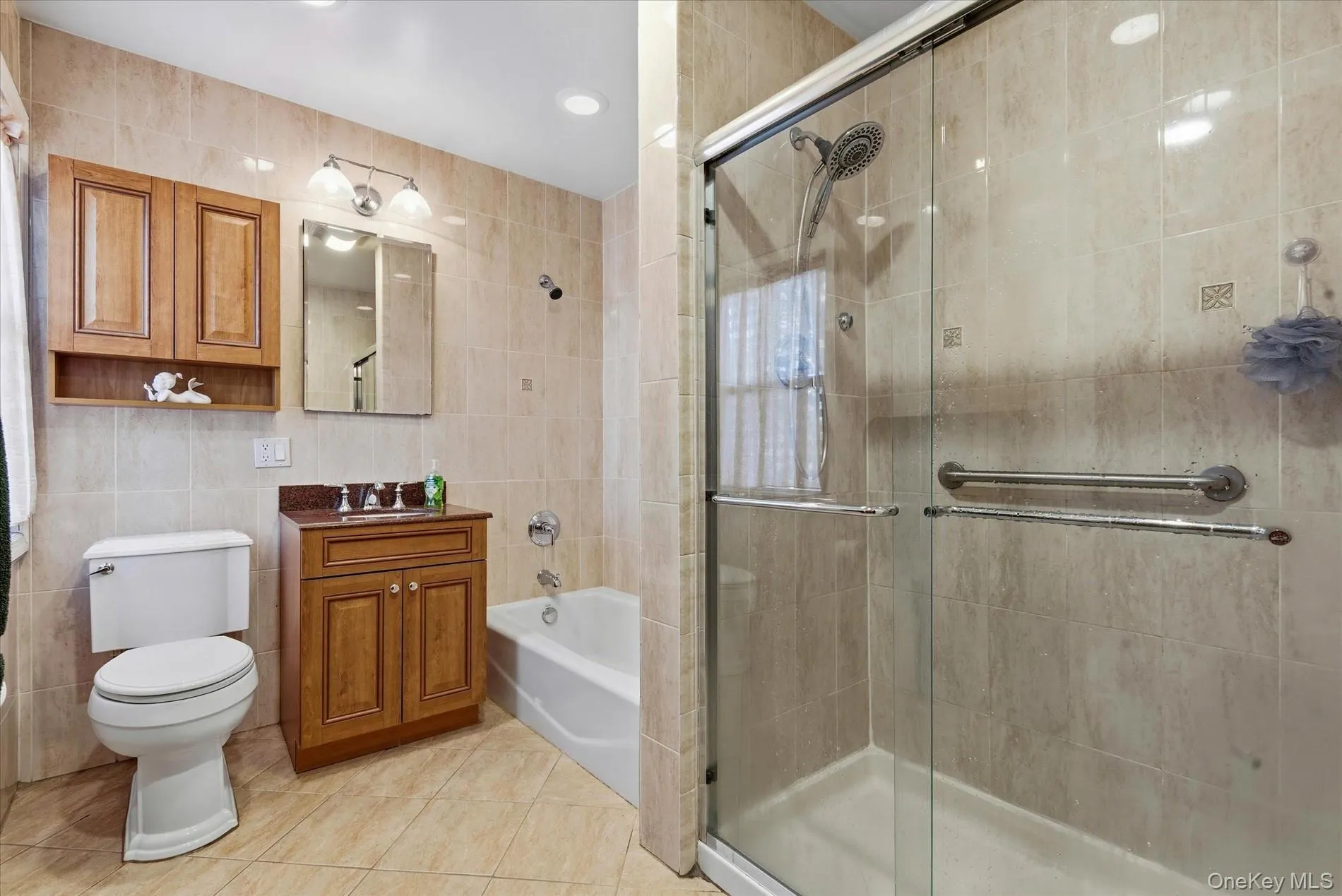 Bathroom featuring tile walls, light tile patterned flooring, a stall shower, vanity, and a bath Bathroom featuring tile walls, light tile patterned flooring, a stall shower, vanity, and a bath