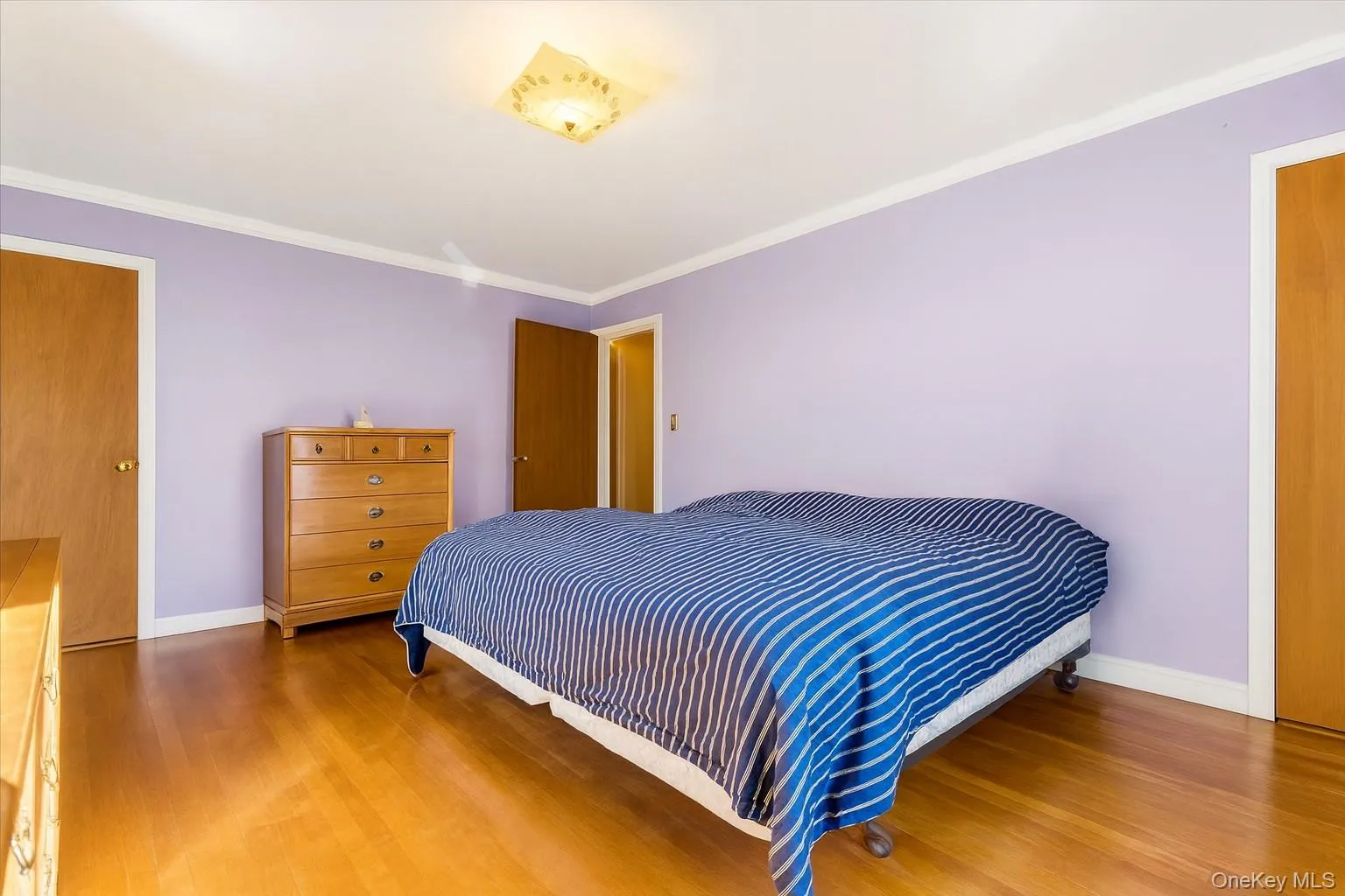 Bedroom with ornamental molding and wood finished floors Bedroom with ornamental molding and wood finished floors