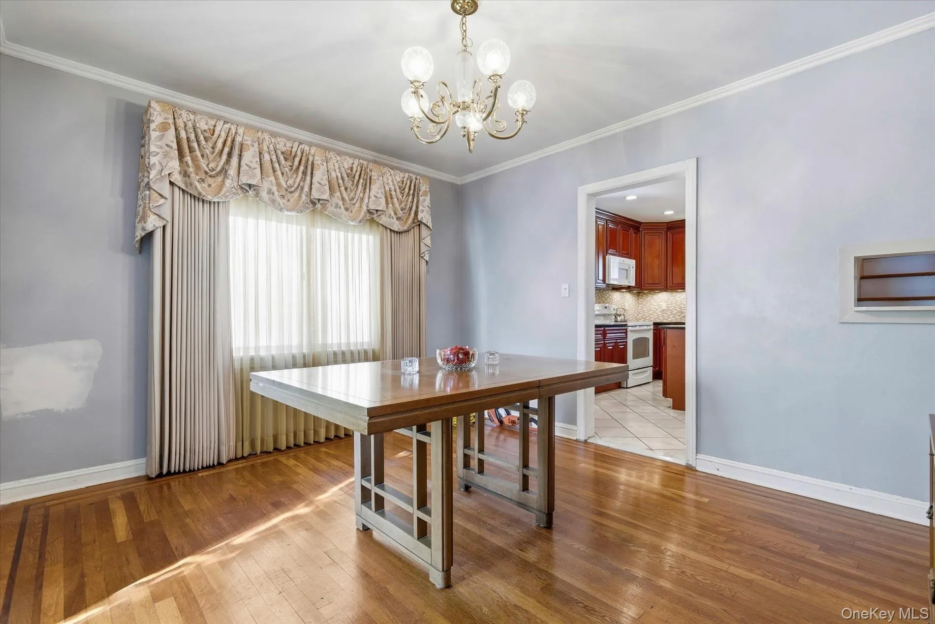 Dining space with ornamental molding, a chandelier, and light wood finished floors Dining space with ornamental molding, a chandelier, and light wood finished floors