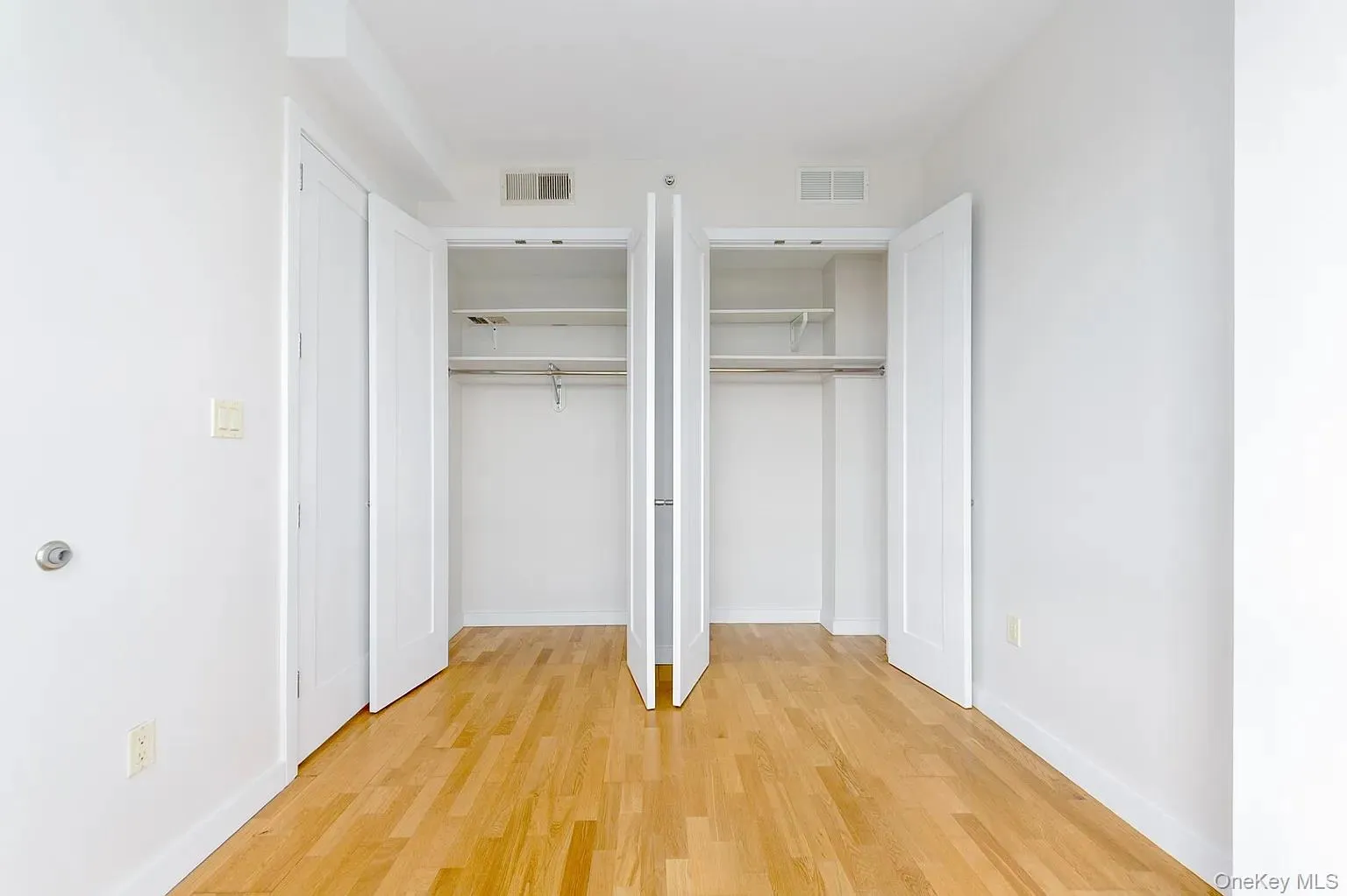 Unfurnished bedroom featuring multiple closets and light wood-style floors Unfurnished bedroom featuring multiple closets and light wood-style floors