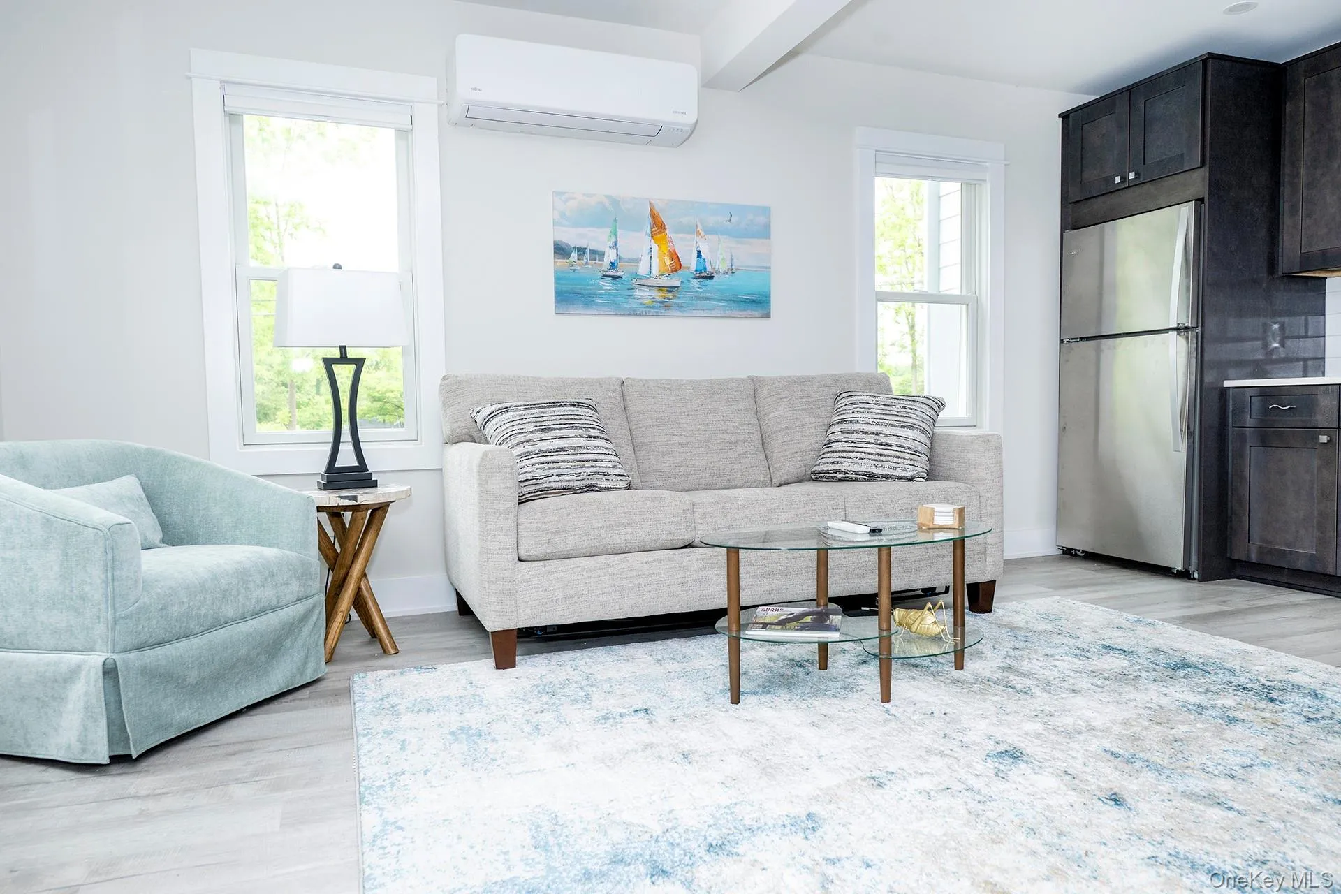 Living room with light wood-type flooring, a wall mounted air conditioner, and beamed ceiling Living room with light wood-type flooring, a wall mounted air conditioner, and beamed ceiling