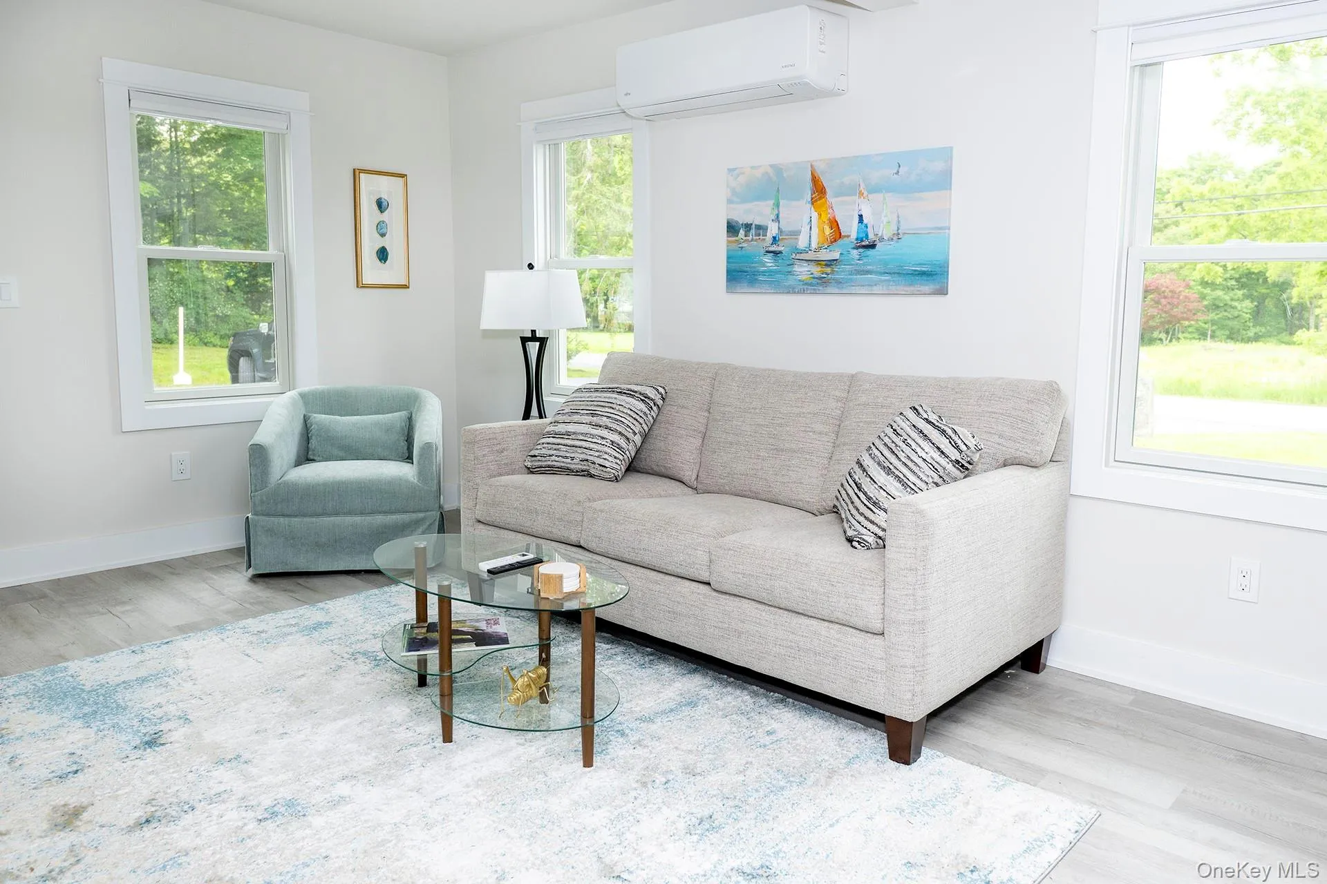 Living area featuring an AC wall unit, light wood-style floors, and plenty of natural light Living area featuring an AC wall unit, light wood-style floors, and plenty of natural light