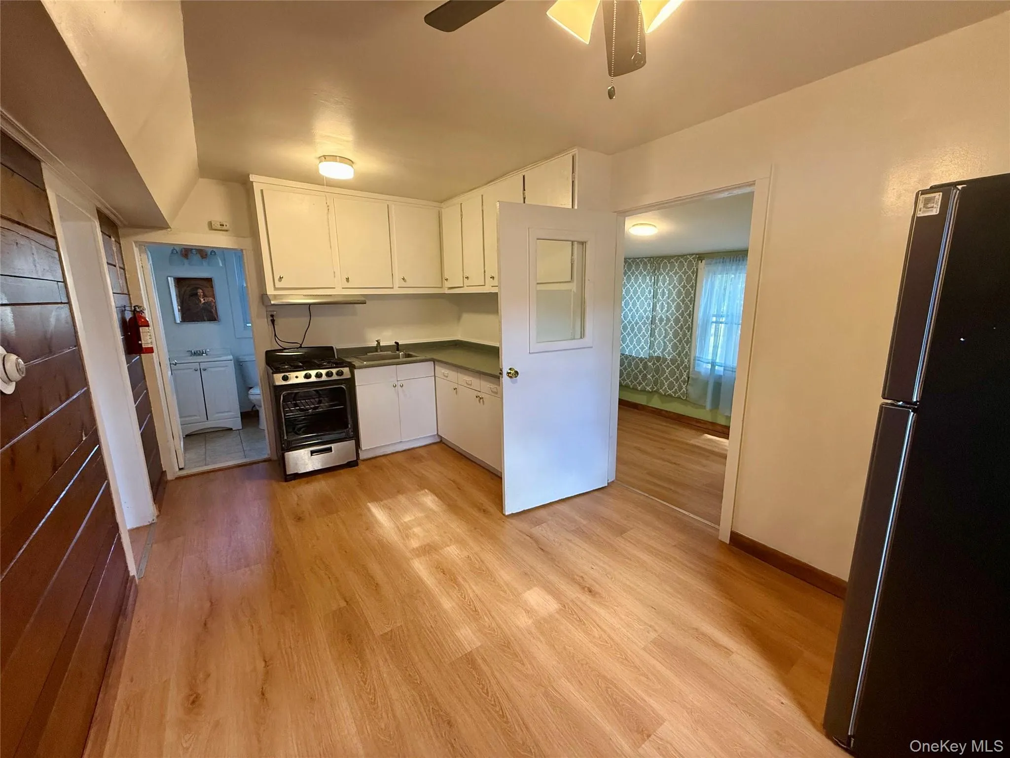 Kitchen with stainless steel appliances, light wood finished floors, white cabinetry, dark countertops, and a ceiling fan Kitchen with stainless steel appliances, light wood finished floors, white cabinetry, dark countertops, and a ceiling fan