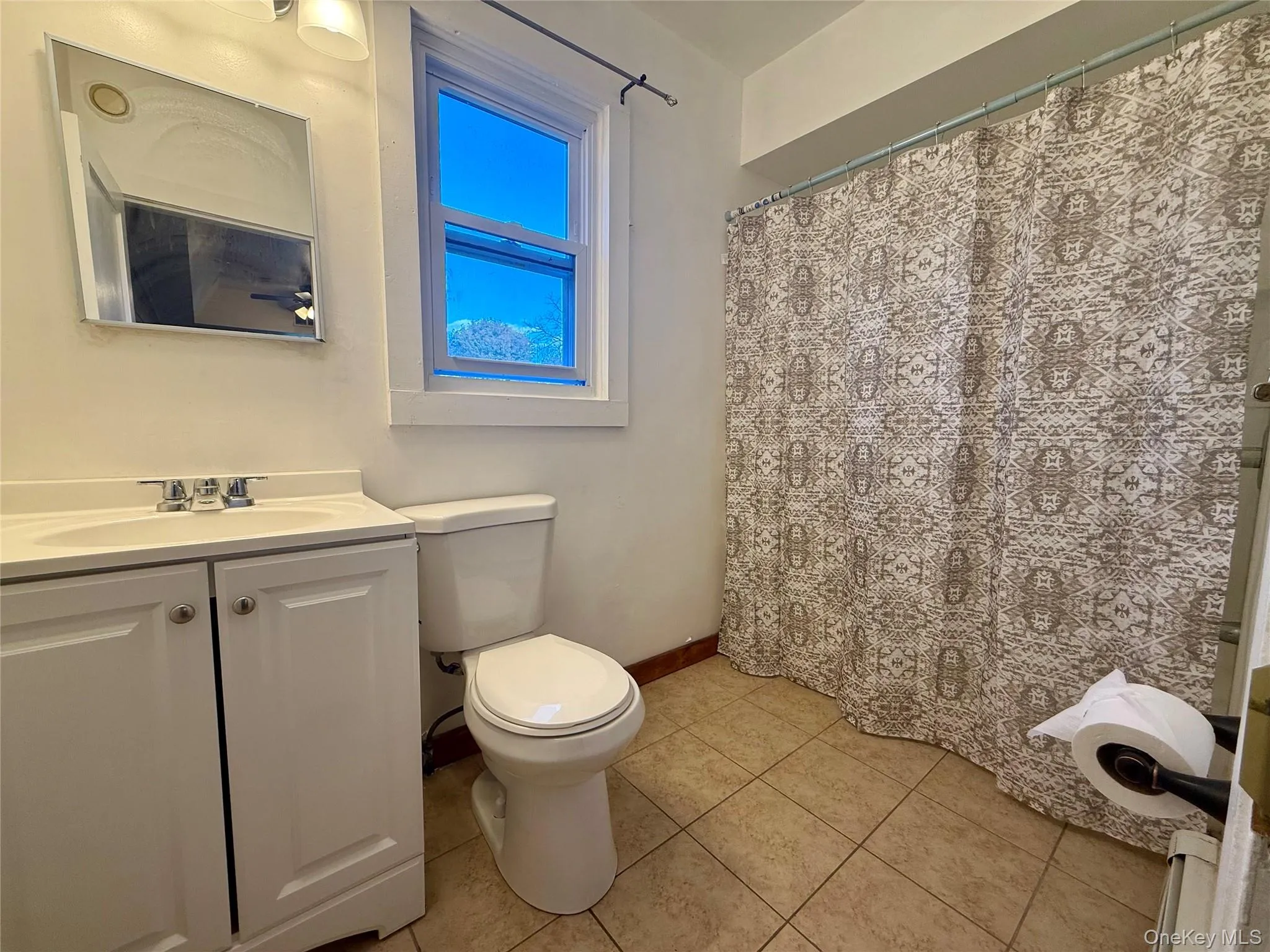 Full bathroom featuring a shower with shower curtain, vanity, and light tile patterned flooring Full bathroom featuring a shower with shower curtain, vanity, and light tile patterned flooring