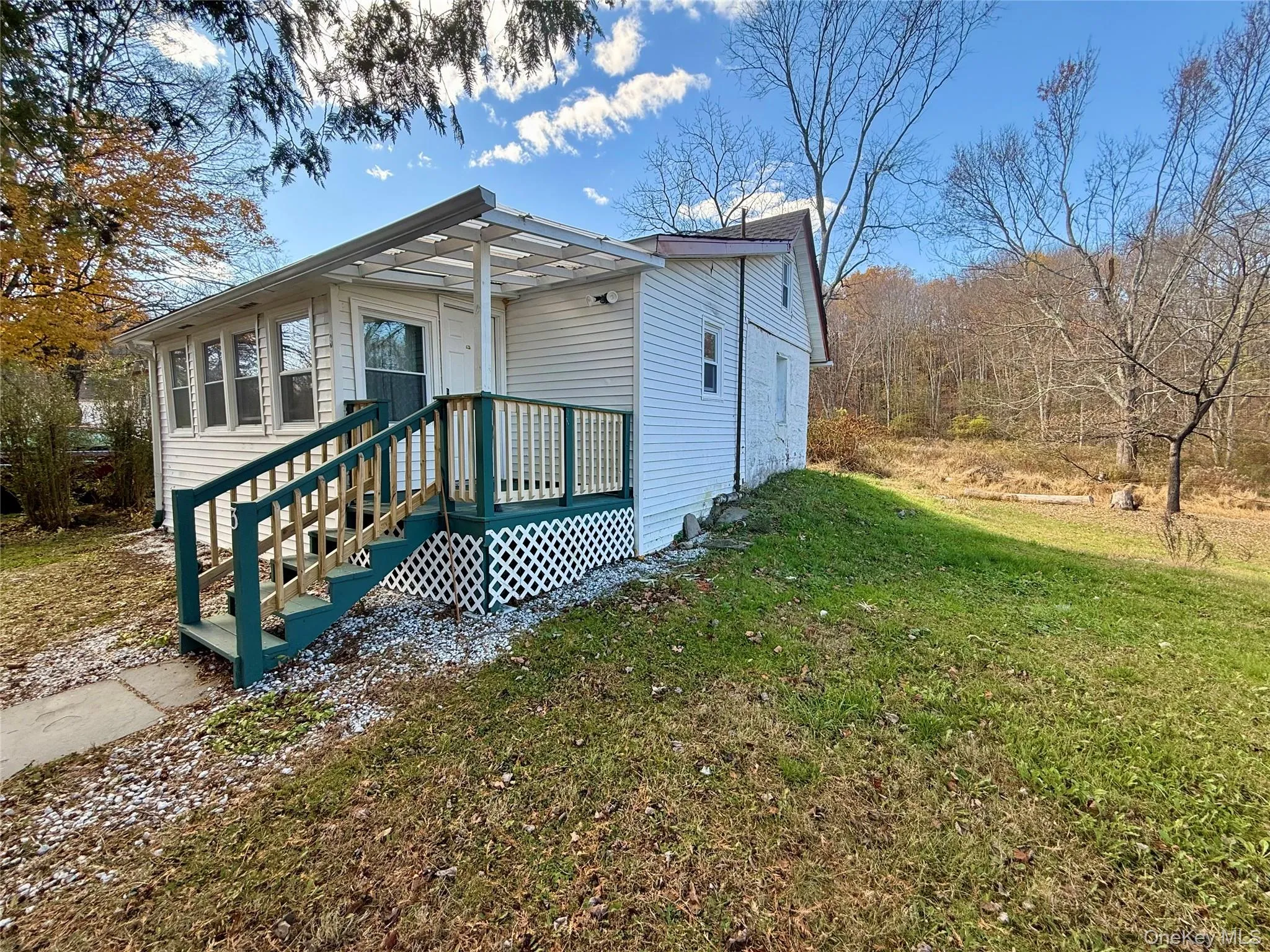 View of front of house featuring a front yard and a wooden deck View of front of house featuring a front yard and a wooden deck