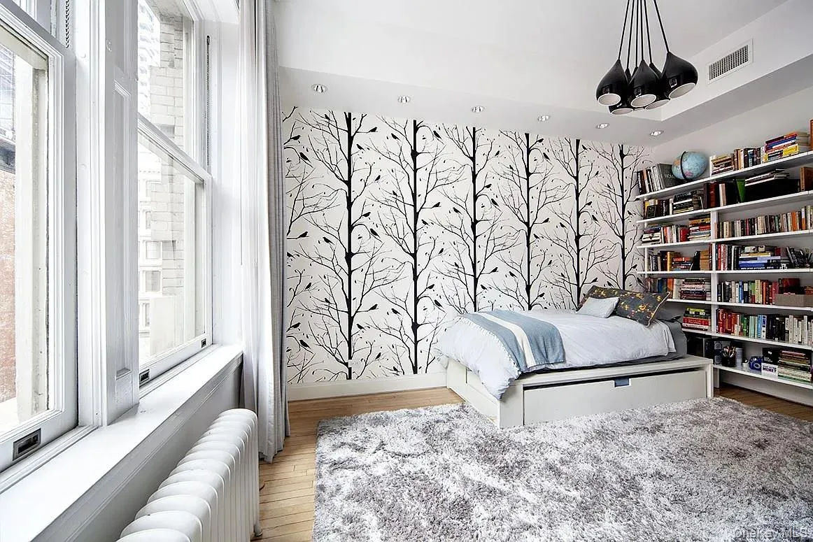 Bedroom featuring multiple windows, a chandelier, radiator, and wood finished floors Bedroom featuring multiple windows, a chandelier, radiator, and wood finished floors