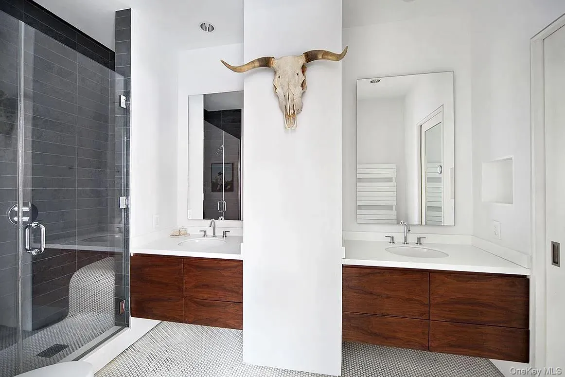 Bathroom featuring two vanities, a shower stall, and light tile patterned floors Bathroom featuring two vanities, a shower stall, and light tile patterned floors