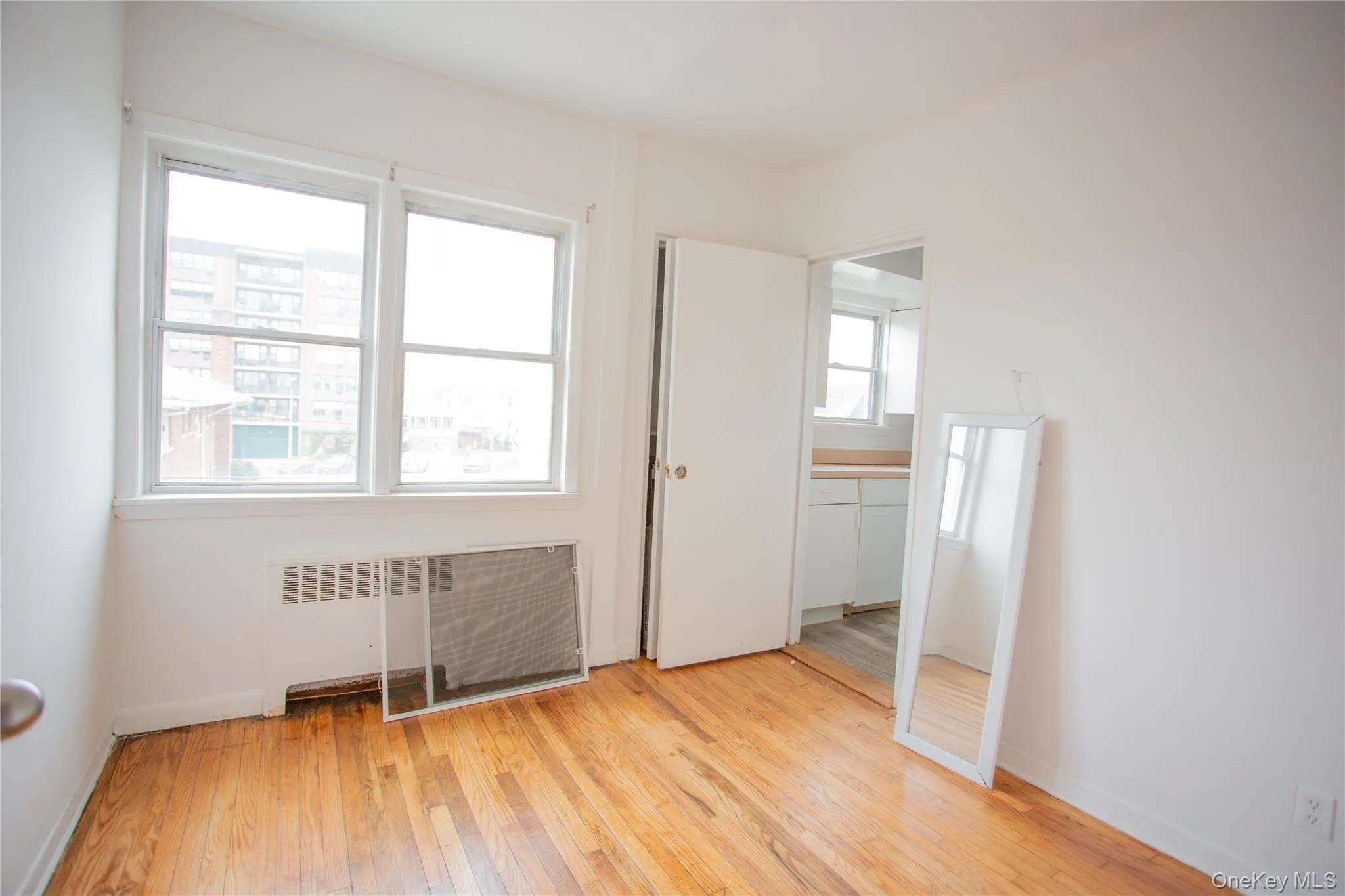 Unfurnished bedroom with radiator heating unit and light wood-type flooring Unfurnished bedroom with radiator heating unit and light wood-type flooring