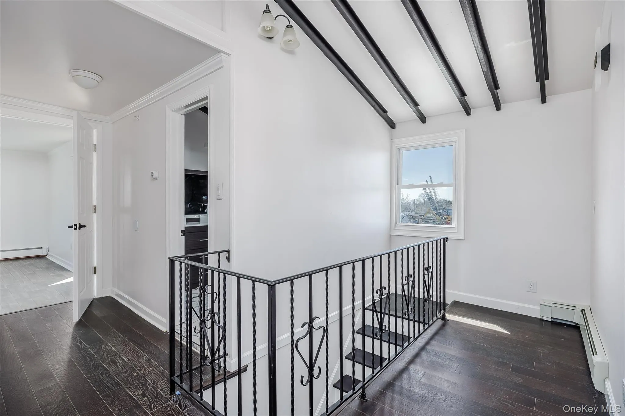 Hall featuring an upstairs landing, dark wood finished floors, and a baseboard heating unit Hall featuring an upstairs landing, dark wood finished floors, and a baseboard heating unit