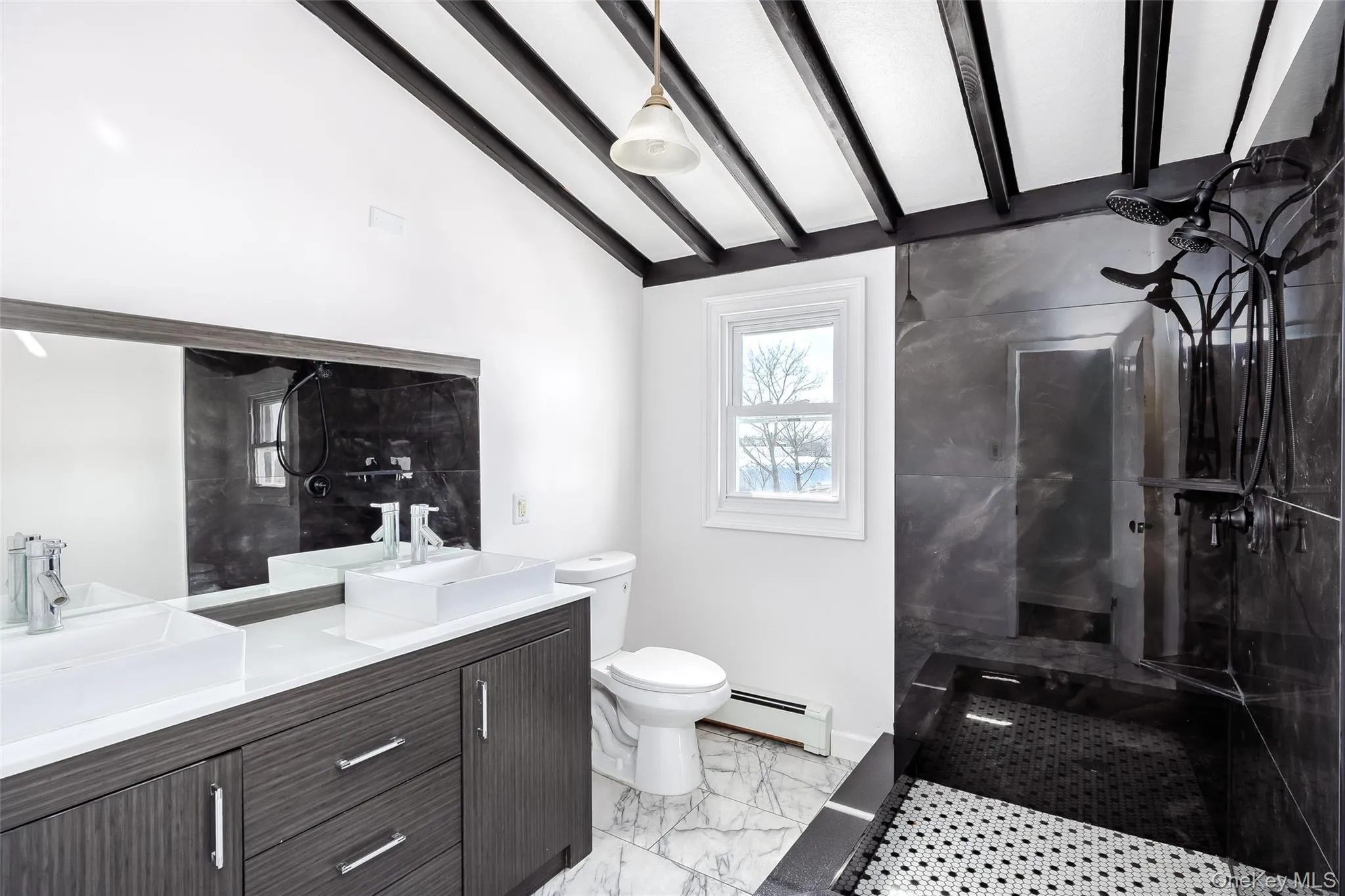 Bathroom featuring a marble finish shower, double vanity, baseboard heating, and light marble finish floors Bathroom featuring a marble finish shower, double vanity, baseboard heating, and light marble finish floors