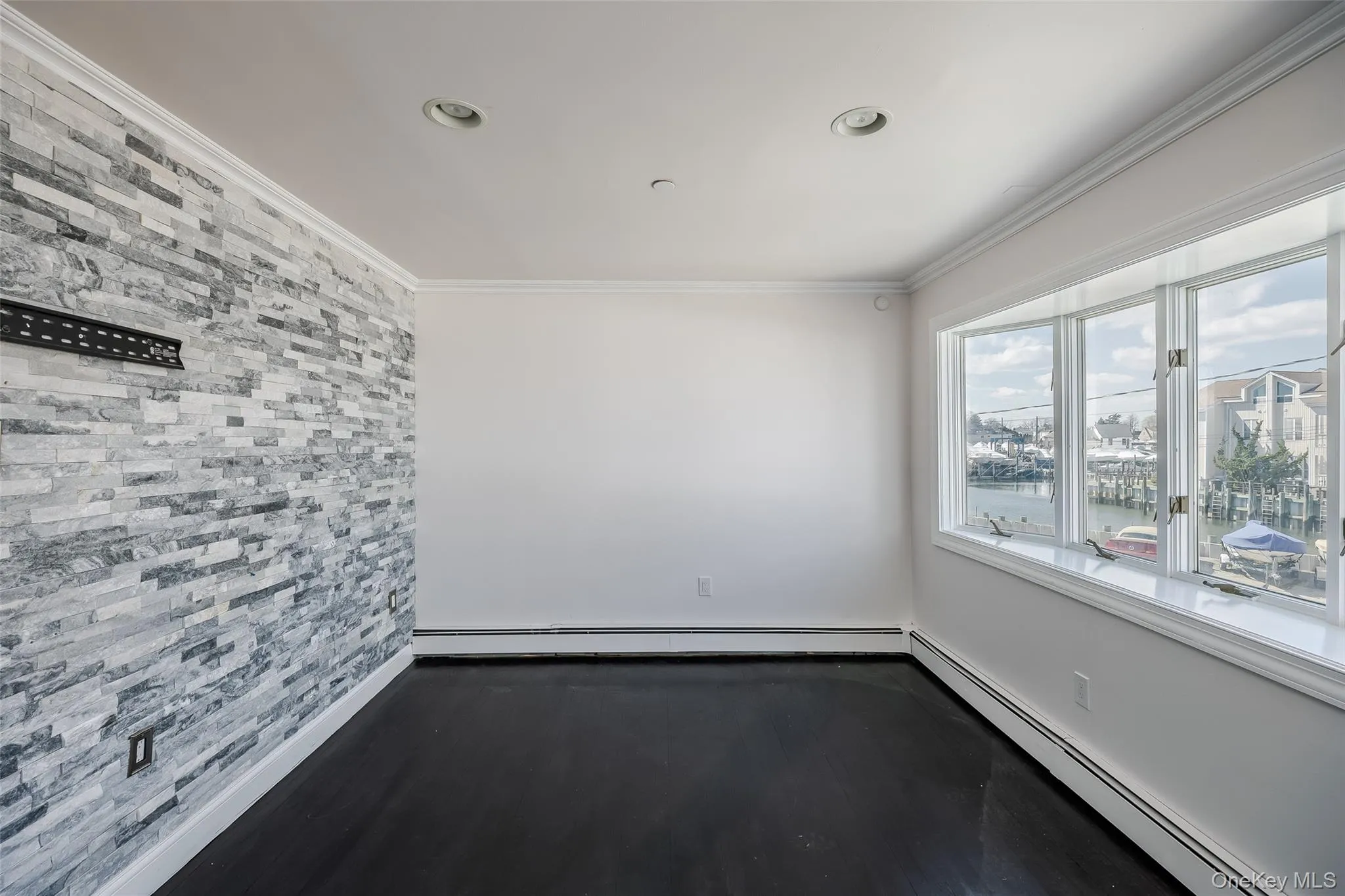 Unfurnished room with ornamental molding, a baseboard heating unit, dark wood-style floors, a water view, and recessed lighting Unfurnished room with ornamental molding, a baseboard heating unit, dark wood-style floors, a water view, and recessed lighting