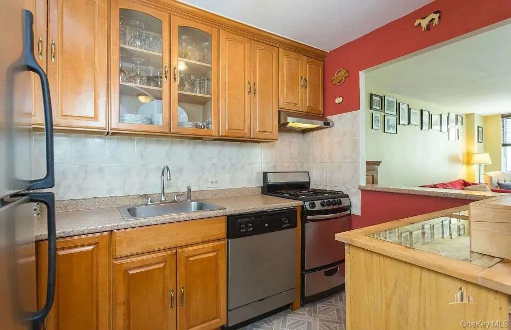 Kitchen with tasteful backsplash, stainless steel appliances, wooden counters, under cabinet range hood, and brown cabinetry Kitchen with tasteful backsplash, stainless steel appliances, wooden counters, under cabinet range hood, and brown cabinetry