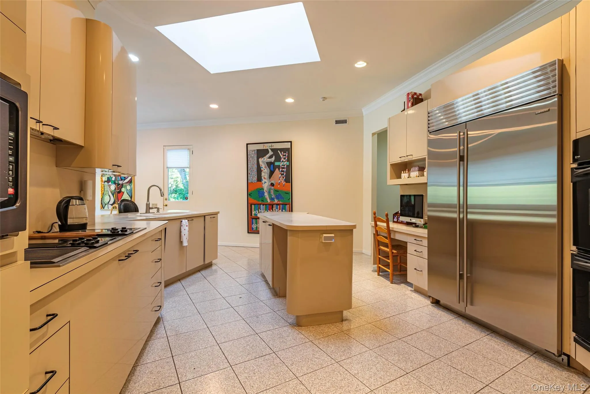 Kitchen with ornamental molding, a skylight, black appliances, a kitchen island, and light countertops Kitchen with ornamental molding, a skylight, black appliances, a kitchen island, and light countertops