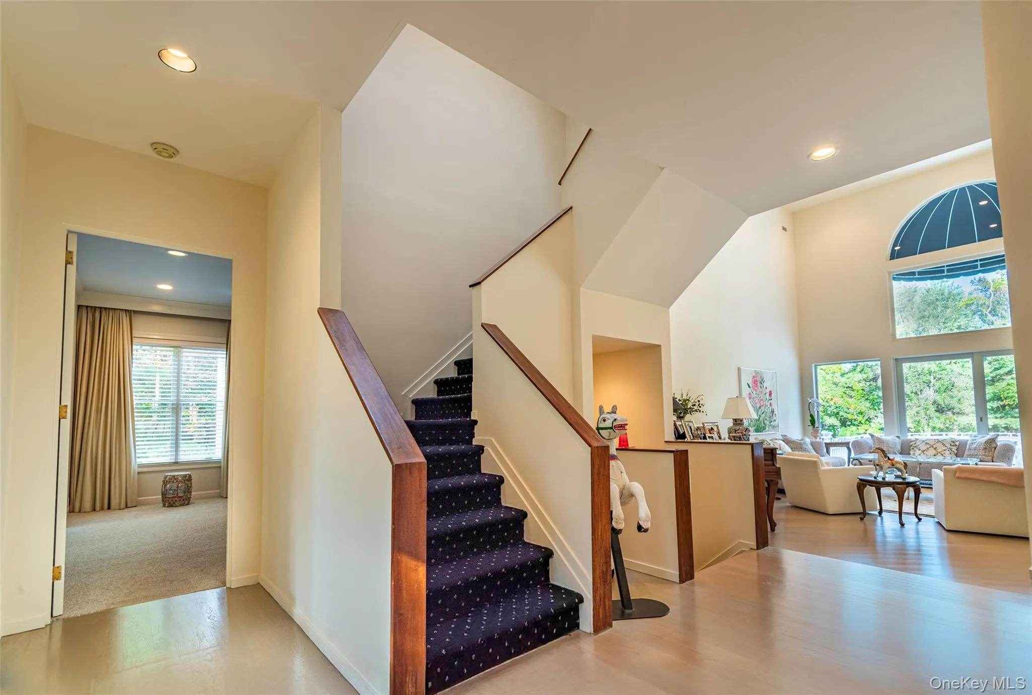 Stairway with recessed lighting, wood finished floors, and a high ceiling Stairway with recessed lighting, wood finished floors, and a high ceiling