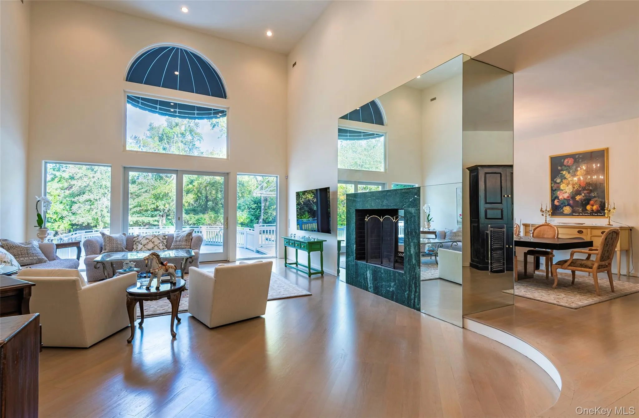 Living room with a high ceiling, wood finished floors, and a fireplace Living room with a high ceiling, wood finished floors, and a fireplace