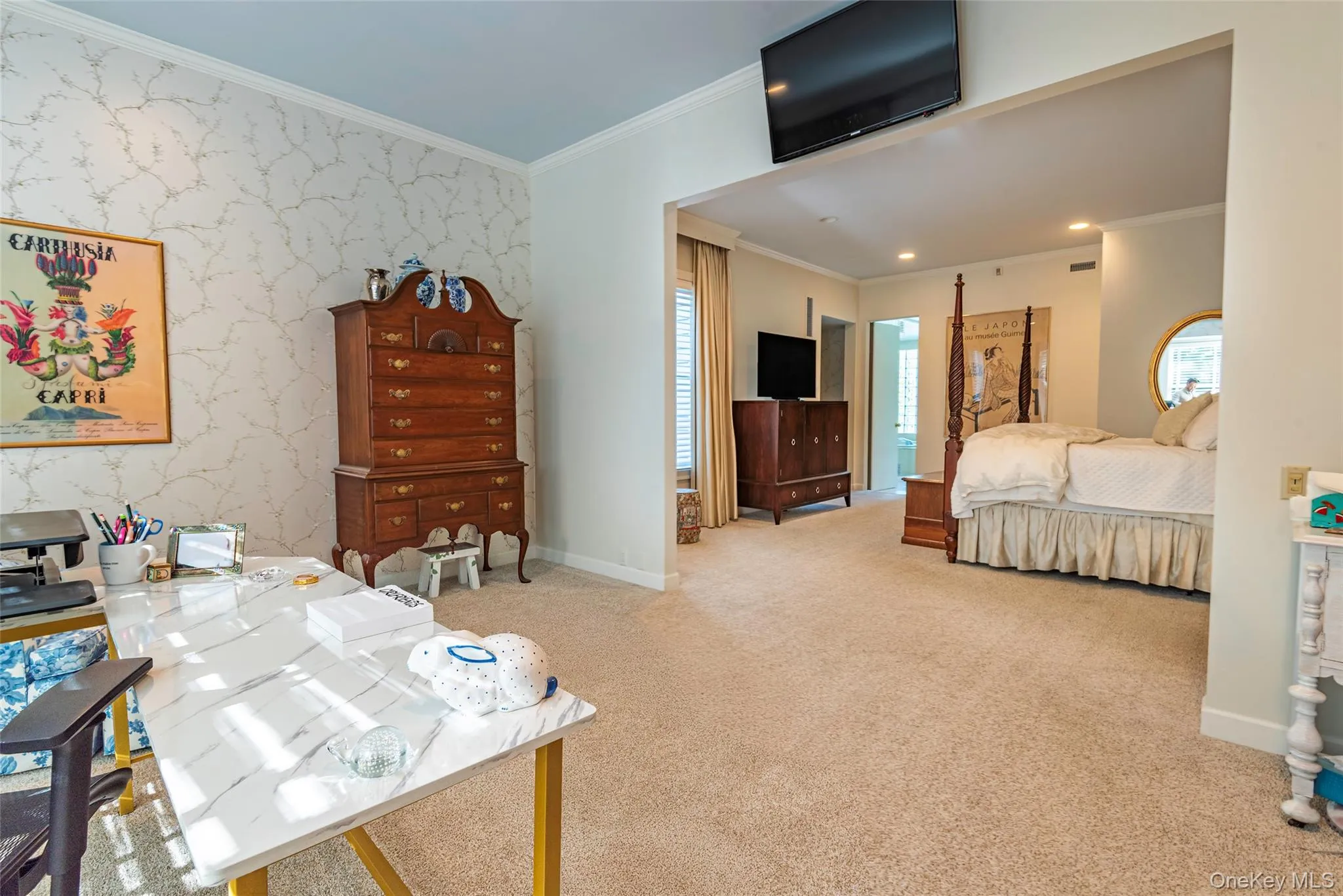 Bedroom with ornamental molding, wallpapered walls, light colored carpet, and an accent wall Bedroom with ornamental molding, wallpapered walls, light colored carpet, and an accent wall