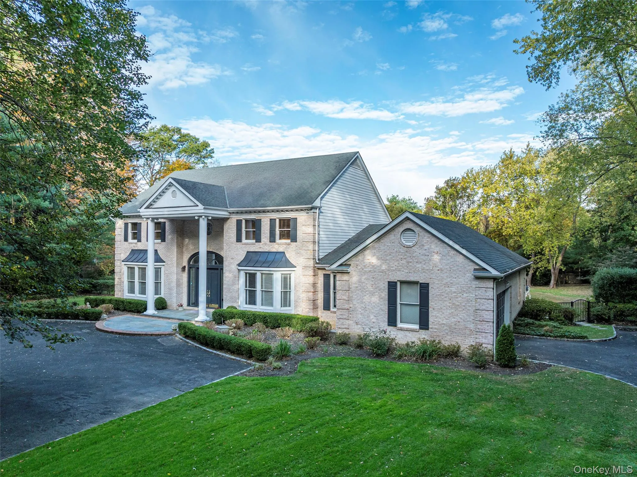 Greek revival inspired property featuring a front yard, brick siding, and roof with shingles Greek revival inspired property featuring a front yard, brick siding, and roof with shingles