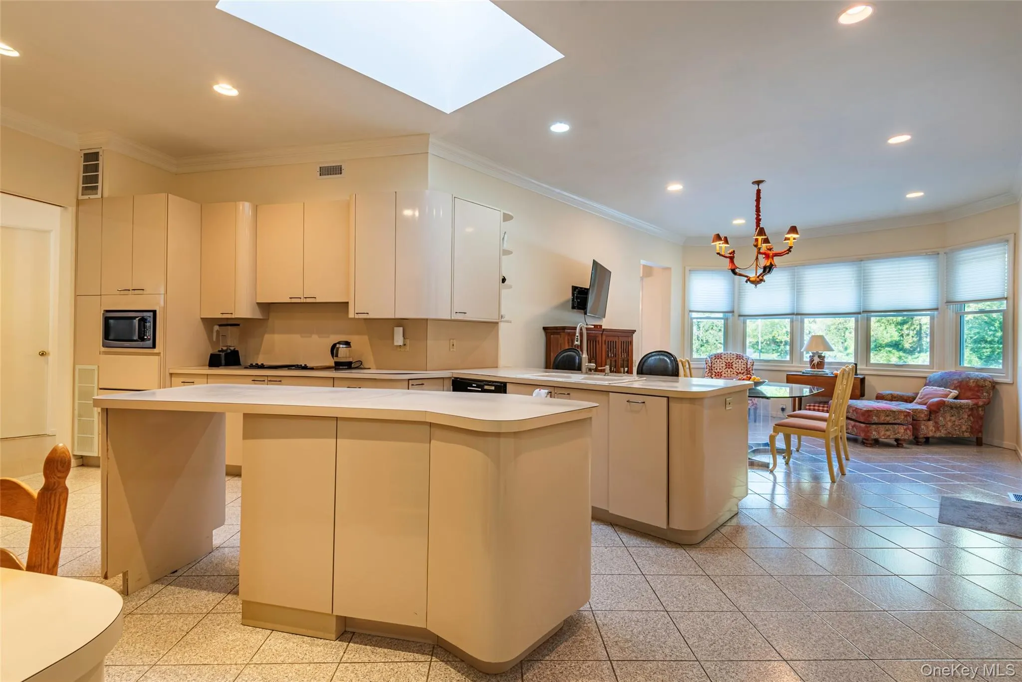 Kitchen with crown molding, a peninsula, recessed lighting, light countertops, and a skylight Kitchen with crown molding, a peninsula, recessed lighting, light countertops, and a skylight
