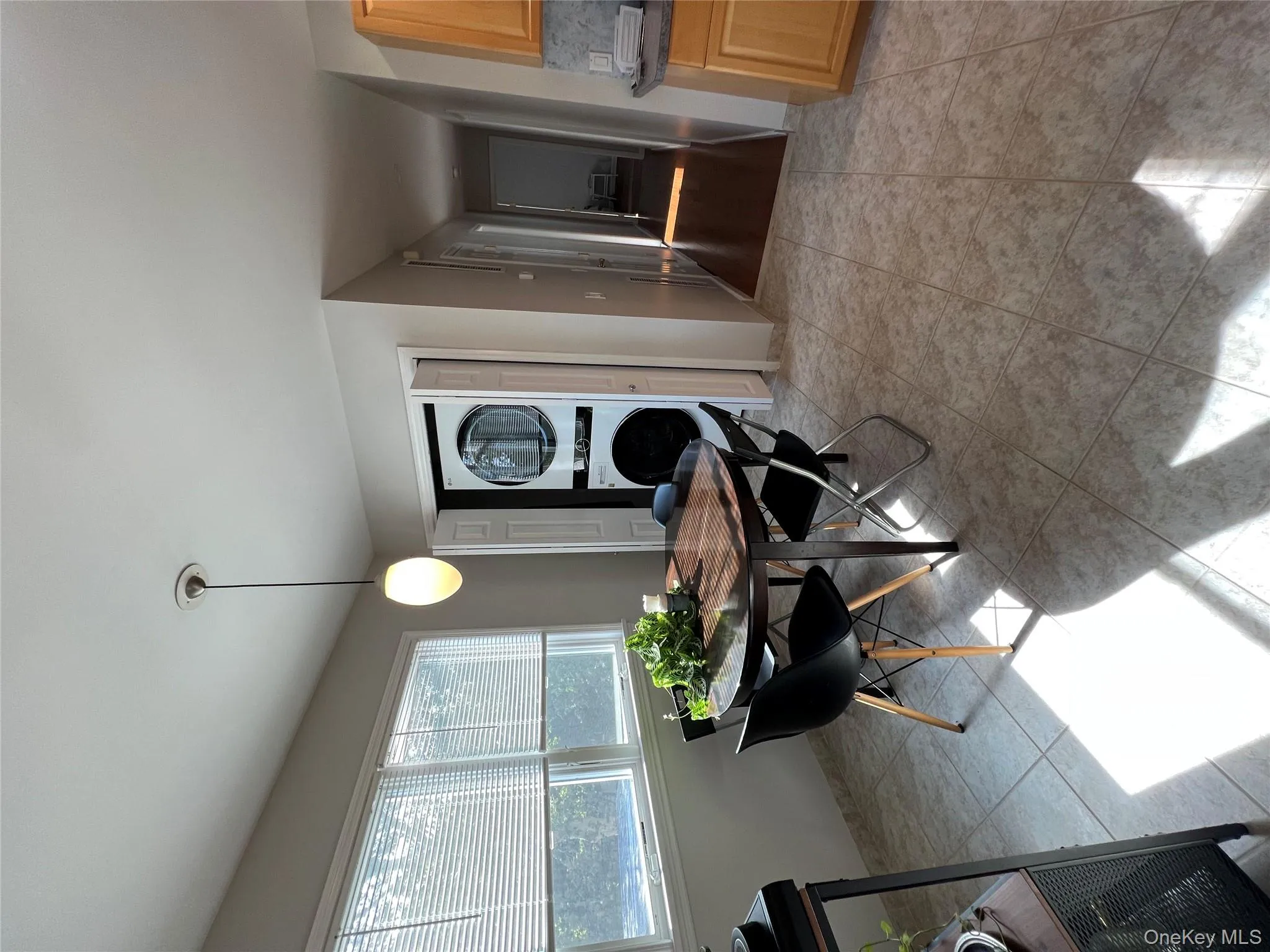 Dining room with stacked washing machine and dryer and light tile patterned floors Dining room with stacked washing machine and dryer and light tile patterned floors