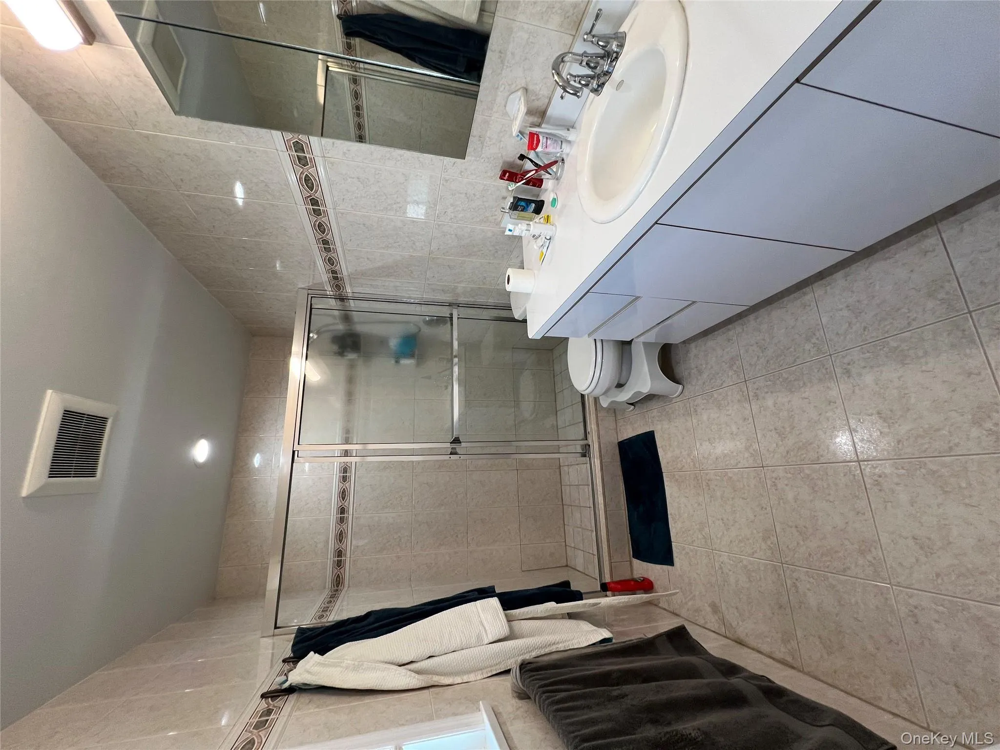 Bathroom with tile walls, vanity, light tile patterned floors, a stall shower, and recessed lighting Bathroom with tile walls, vanity, light tile patterned floors, a stall shower, and recessed lighting