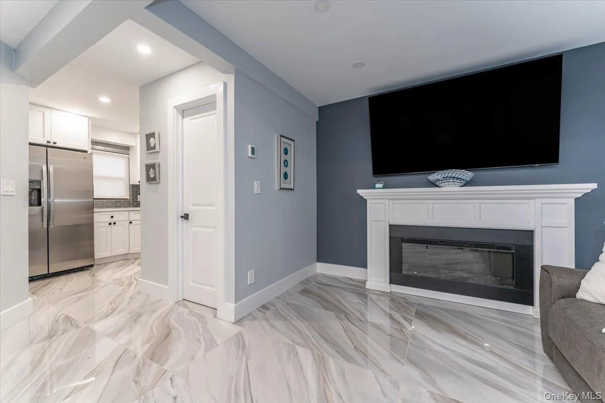 Unfurnished living room featuring a glass covered fireplace, light marble finish flooring, and recessed lighting Unfurnished living room featuring a glass covered fireplace, light marble finish flooring, and recessed lighting