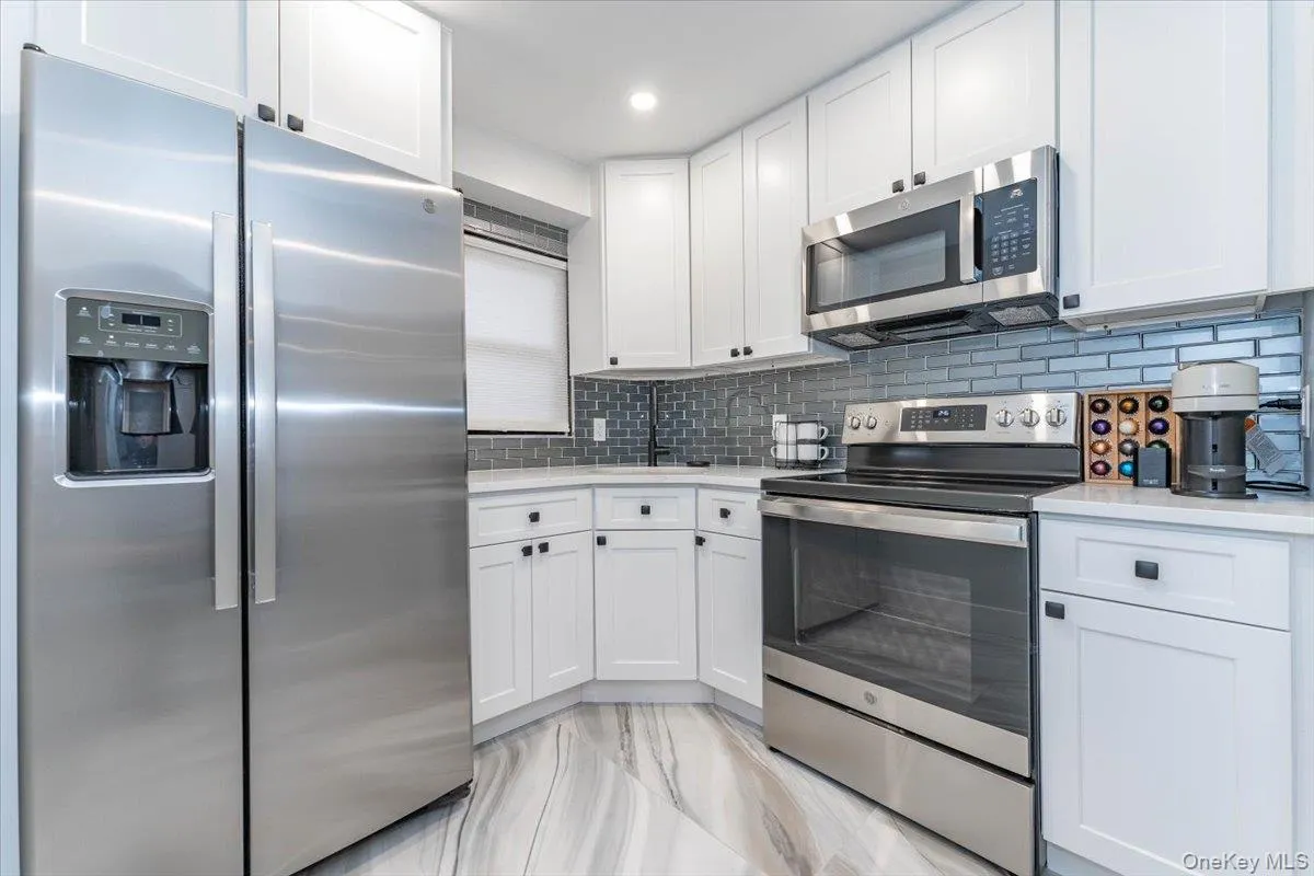 Kitchen with stainless steel appliances, white cabinets, tasteful backsplash, light stone countertops, and recessed lighting Kitchen with stainless steel appliances, white cabinets, tasteful backsplash, light stone countertops, and recessed lighting